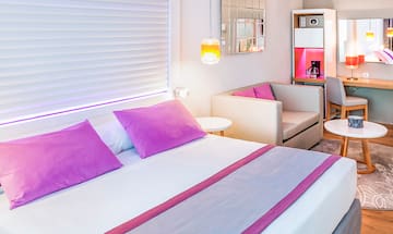 a bed with purple pillows and a couch in a room