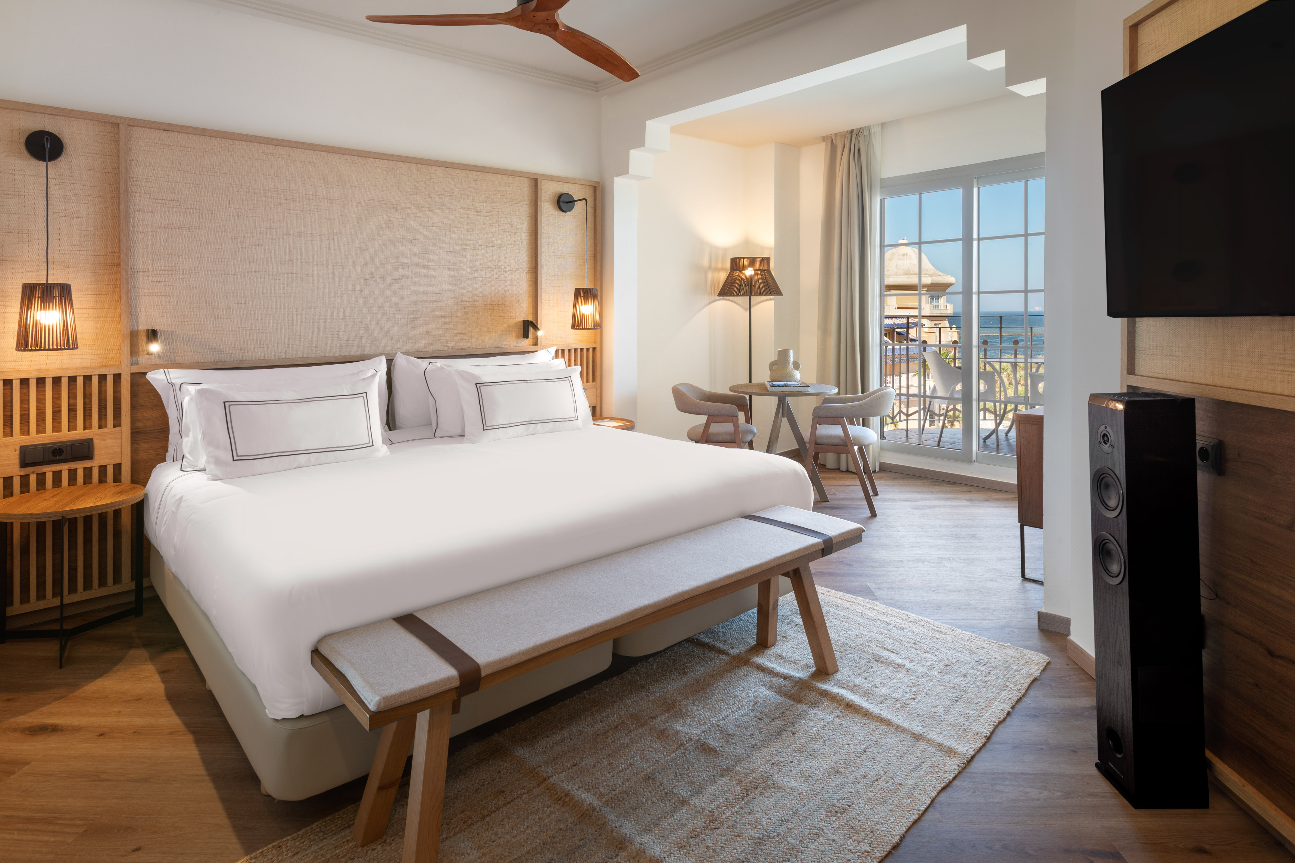 Luxury hotel bedroom with sea view balcony, king bed, and modern wooden decor.
