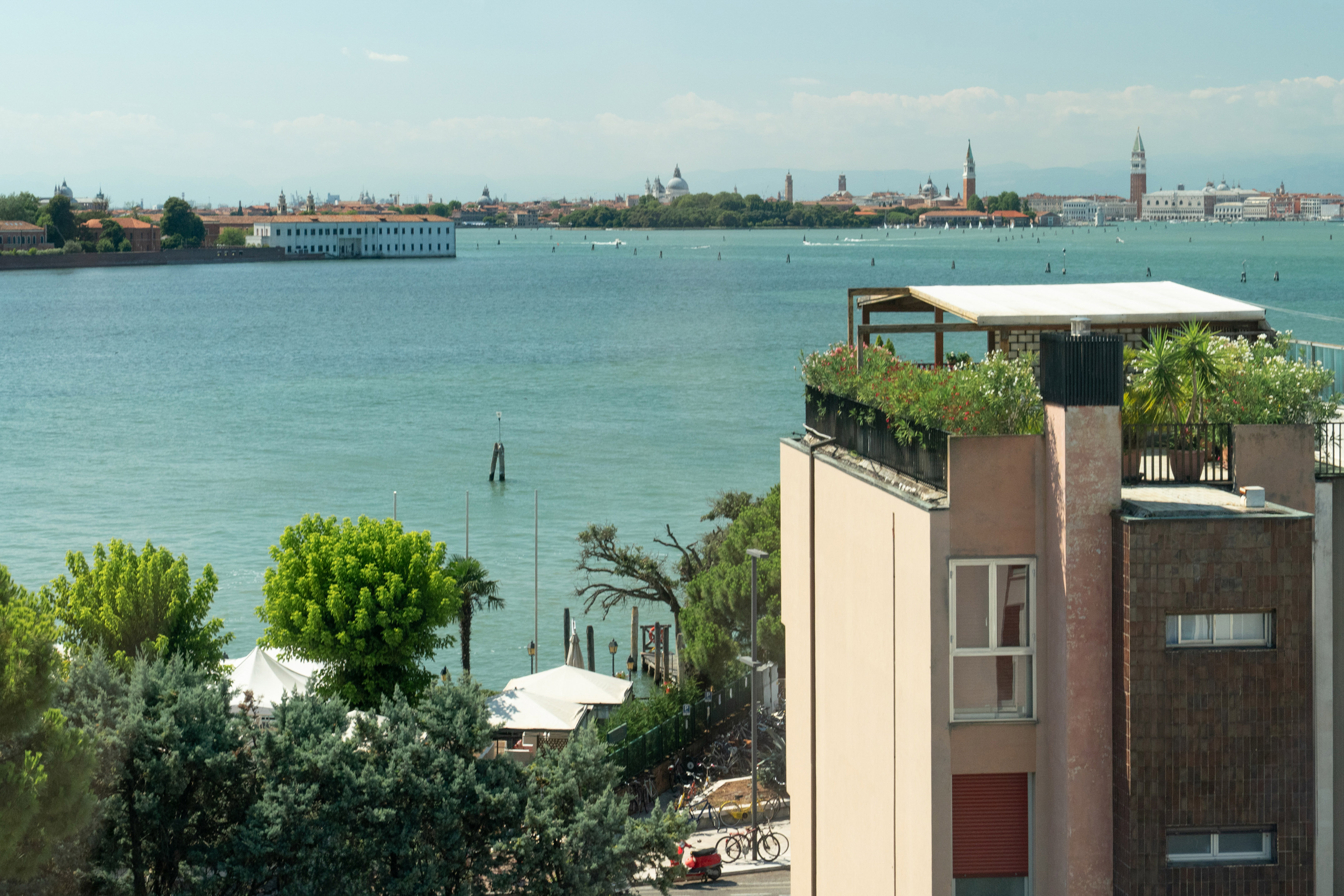 Panoramic Venice cityscape over lagoon from building with rooftop garden.