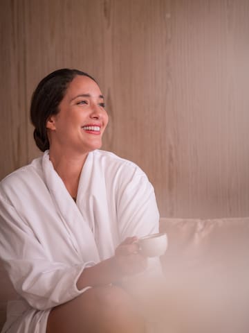 a woman in a white robe holding a cup