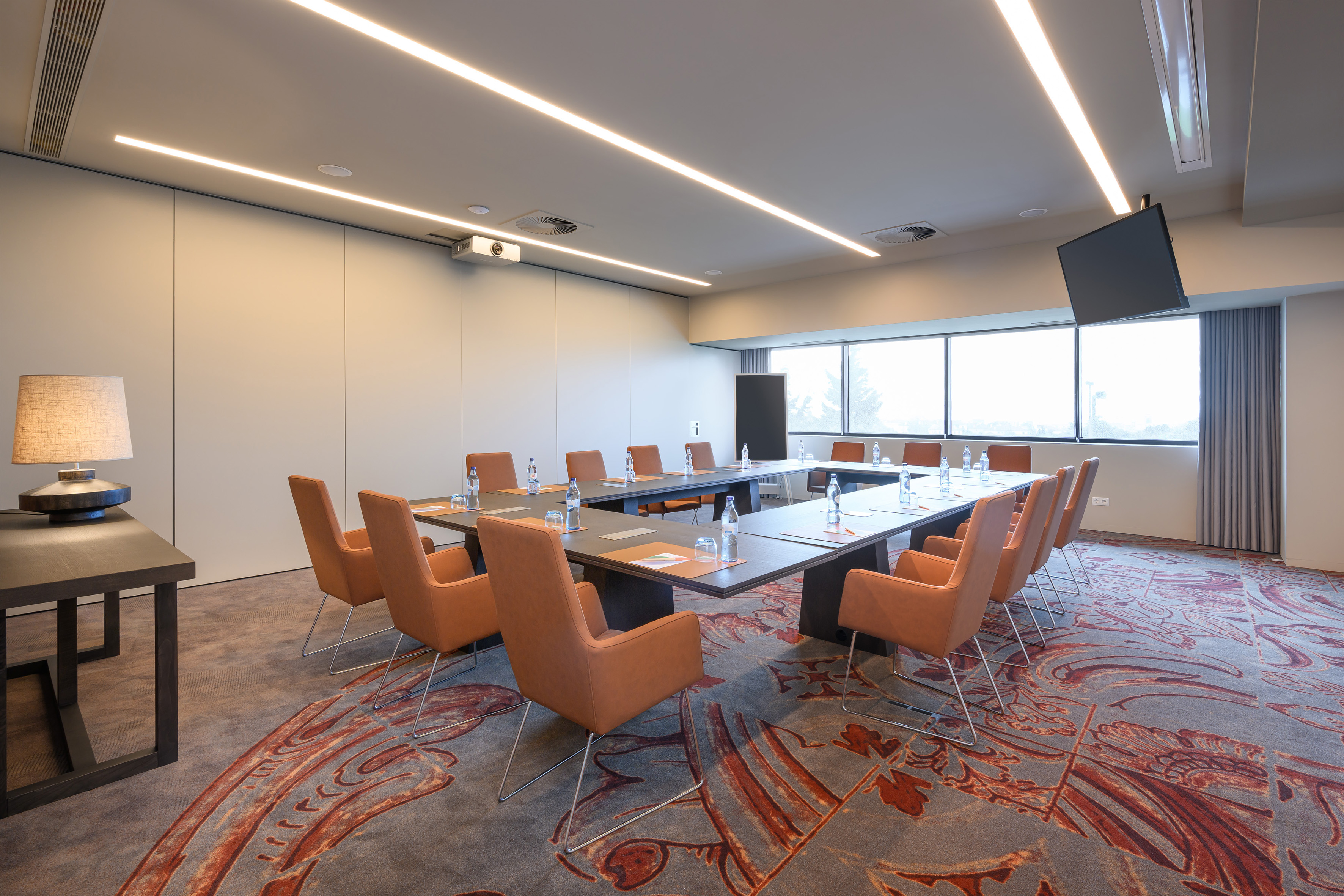 Spacious modern conference room with U-shaped table, orange chairs, and projector.