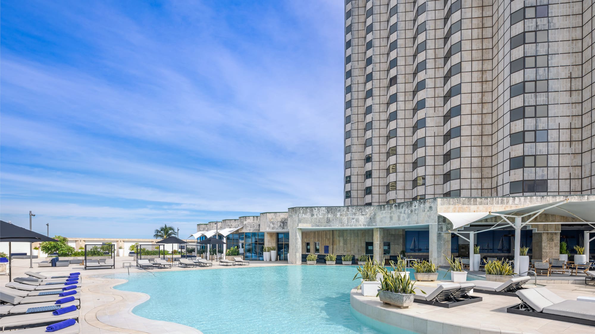 a pool with lounge chairs and a building in the background