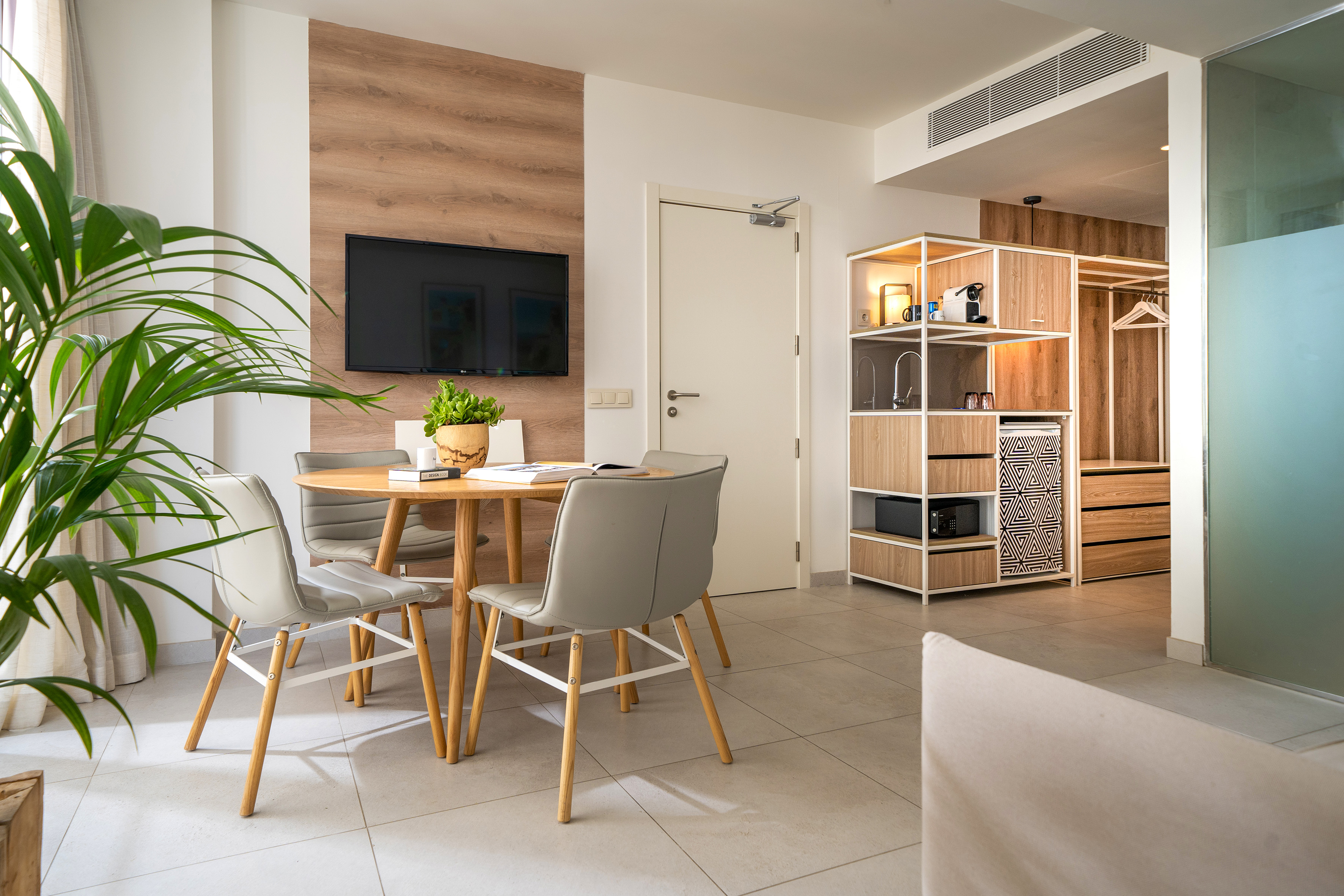 Modern studio apartment with dining area, TV, and integrated kitchenette.