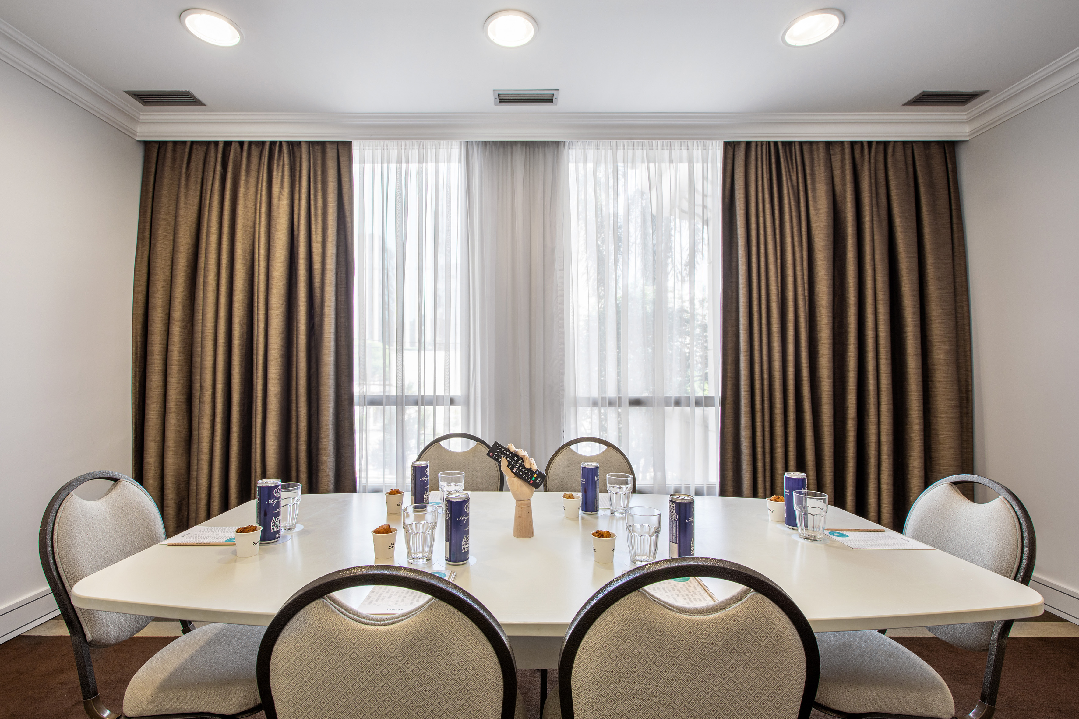 Professional meeting room with conference table, chairs, and window curtains.