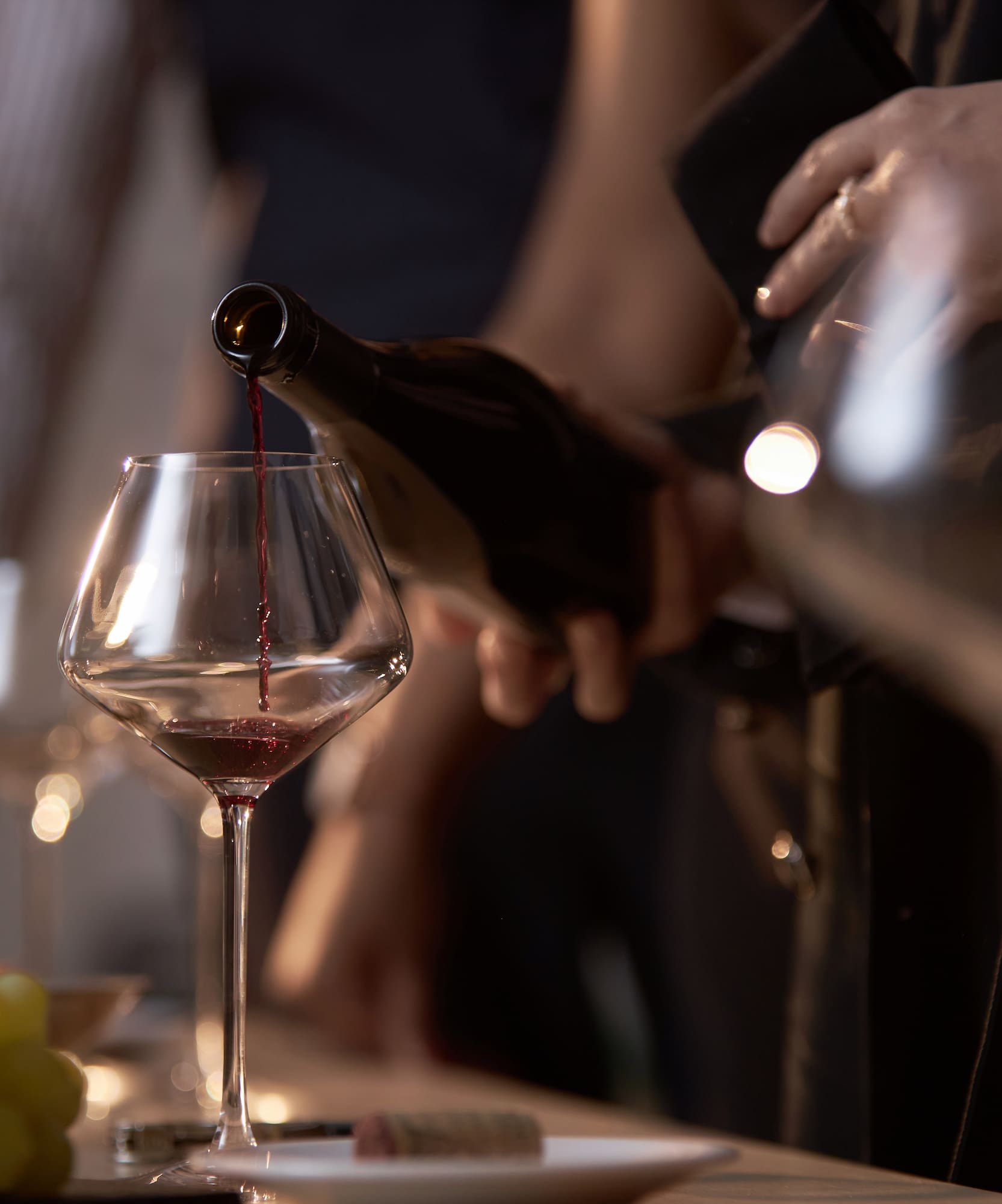 Red wine pouring from bottle into a stemmed wine glass.