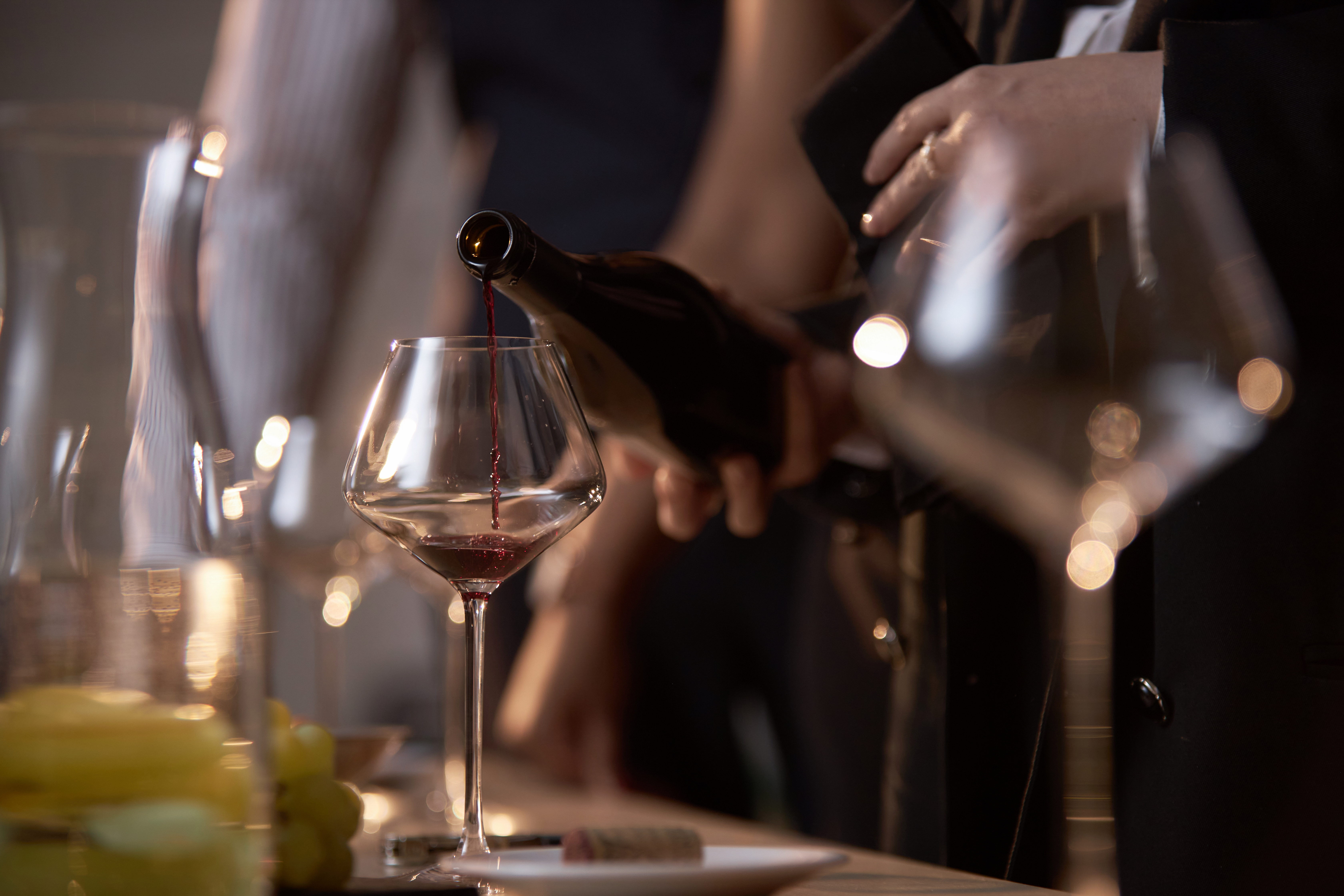 Red wine pouring from bottle into a stemmed wine glass.