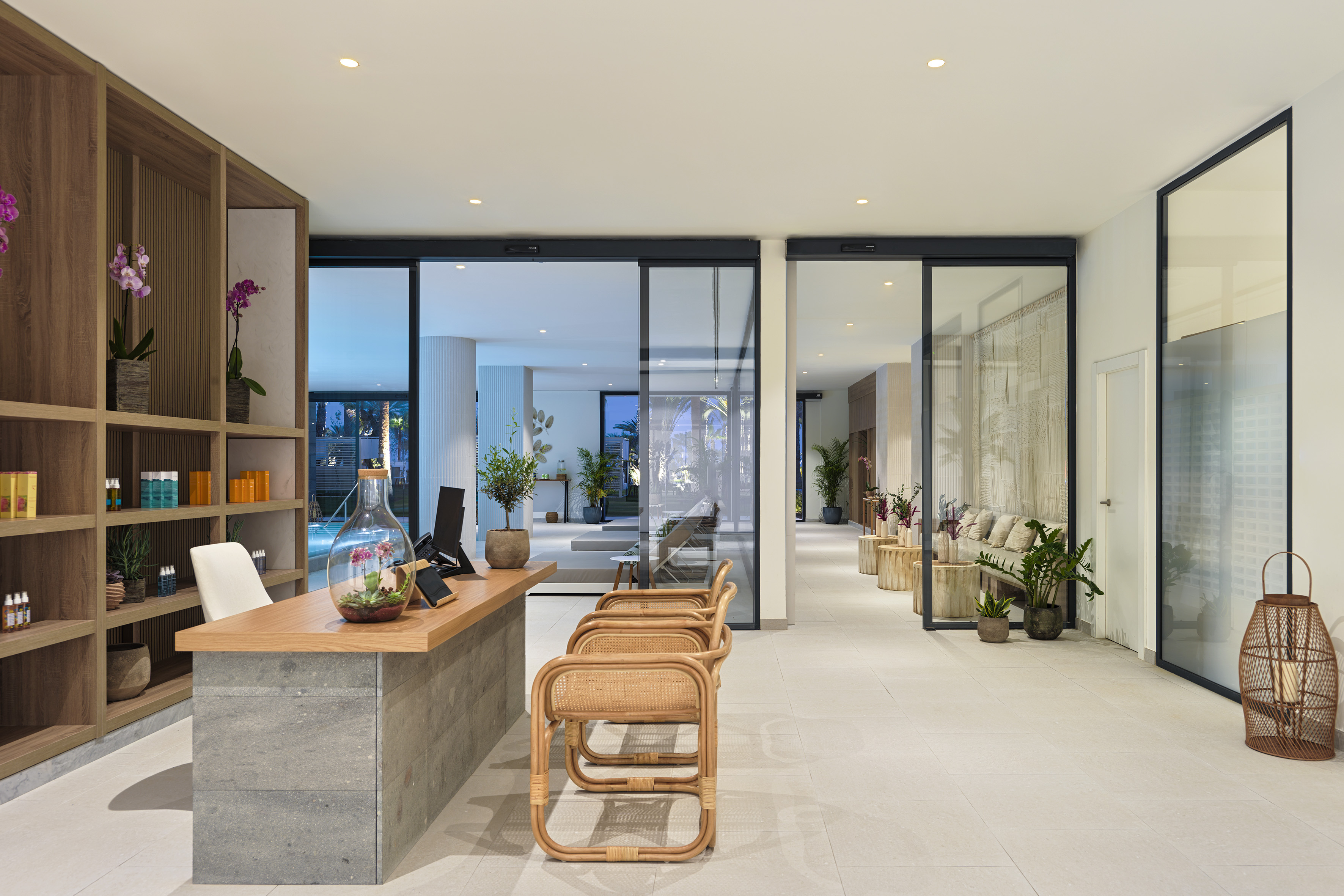 Tropical resort reception with wood desk, rattan chairs, and modern pool view.