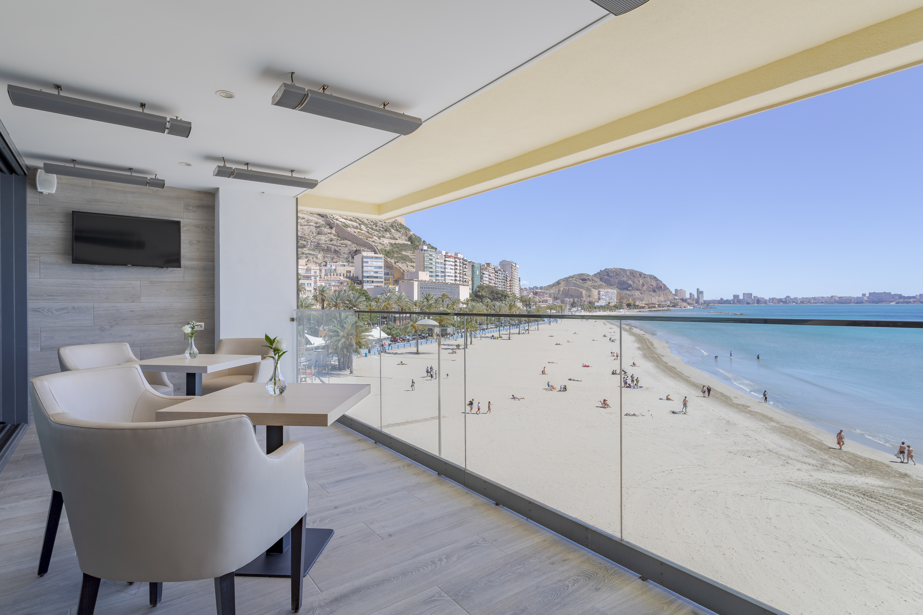 Terraza de restaurante con vistas a la playa, el mar y la ciudad costera.