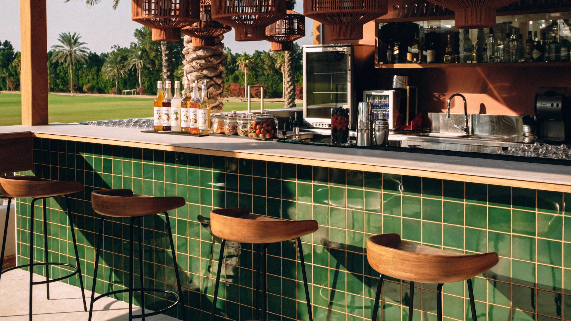 a bar with green tiles and wooden chairs