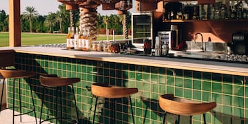 a bar with green tiles and wooden chairs