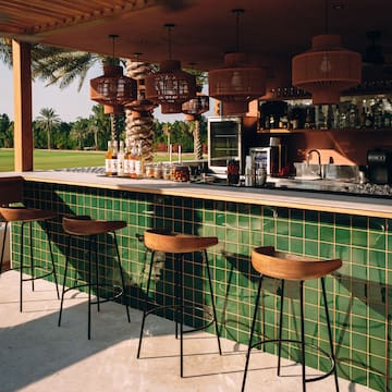 a bar with green tiles and wooden chairs