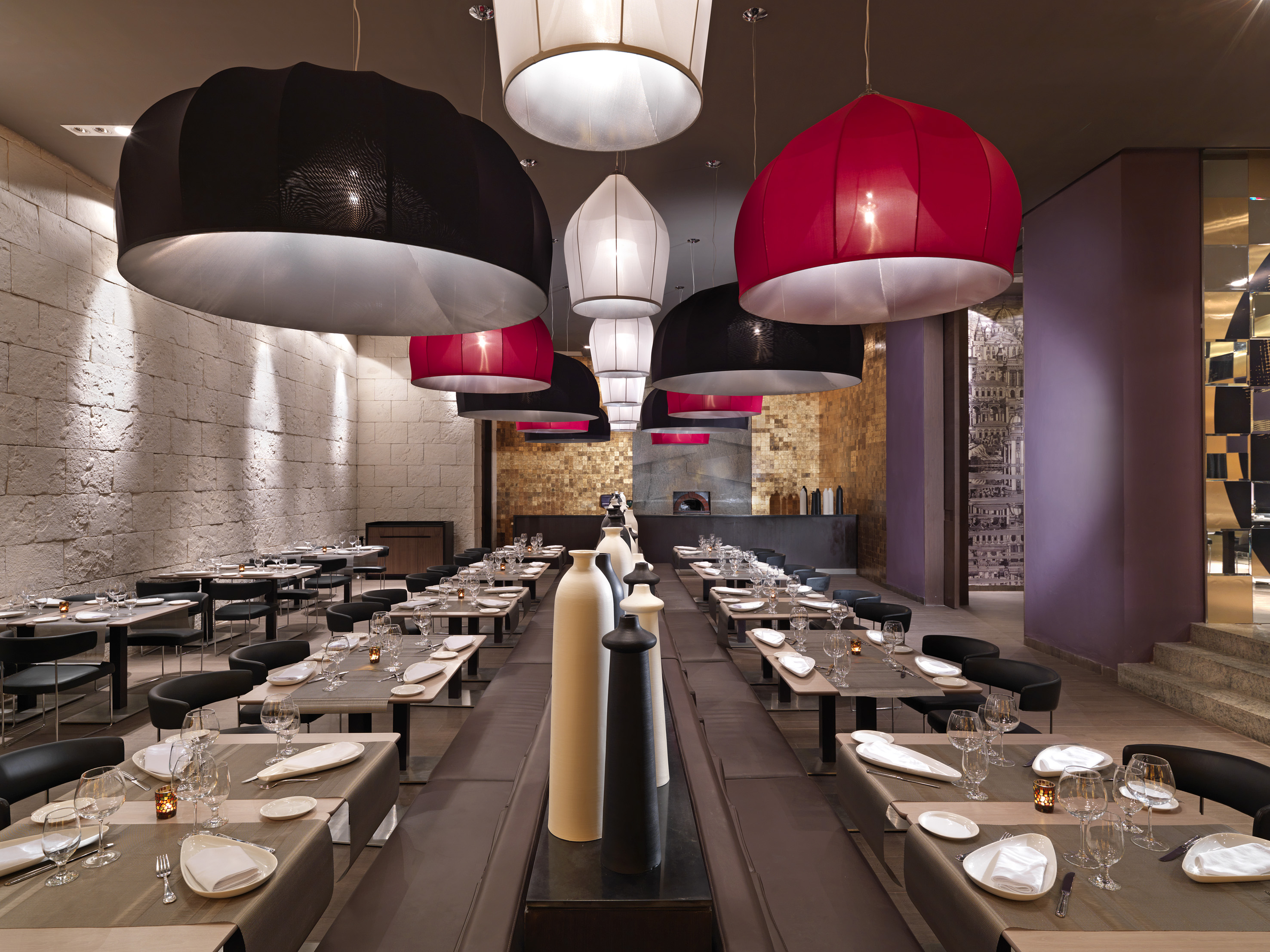 Modern restaurant dining room with decorative pendant lights and set tables.