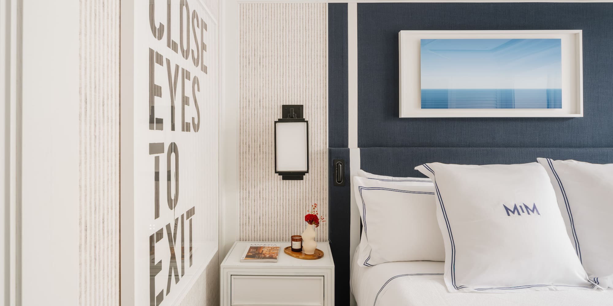 a bed with pillows and a basket on a nightstand