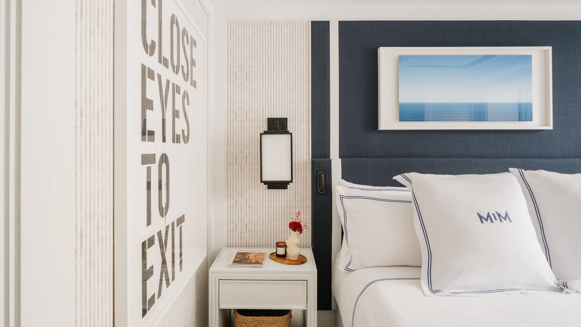 a bed with pillows and a basket on a nightstand