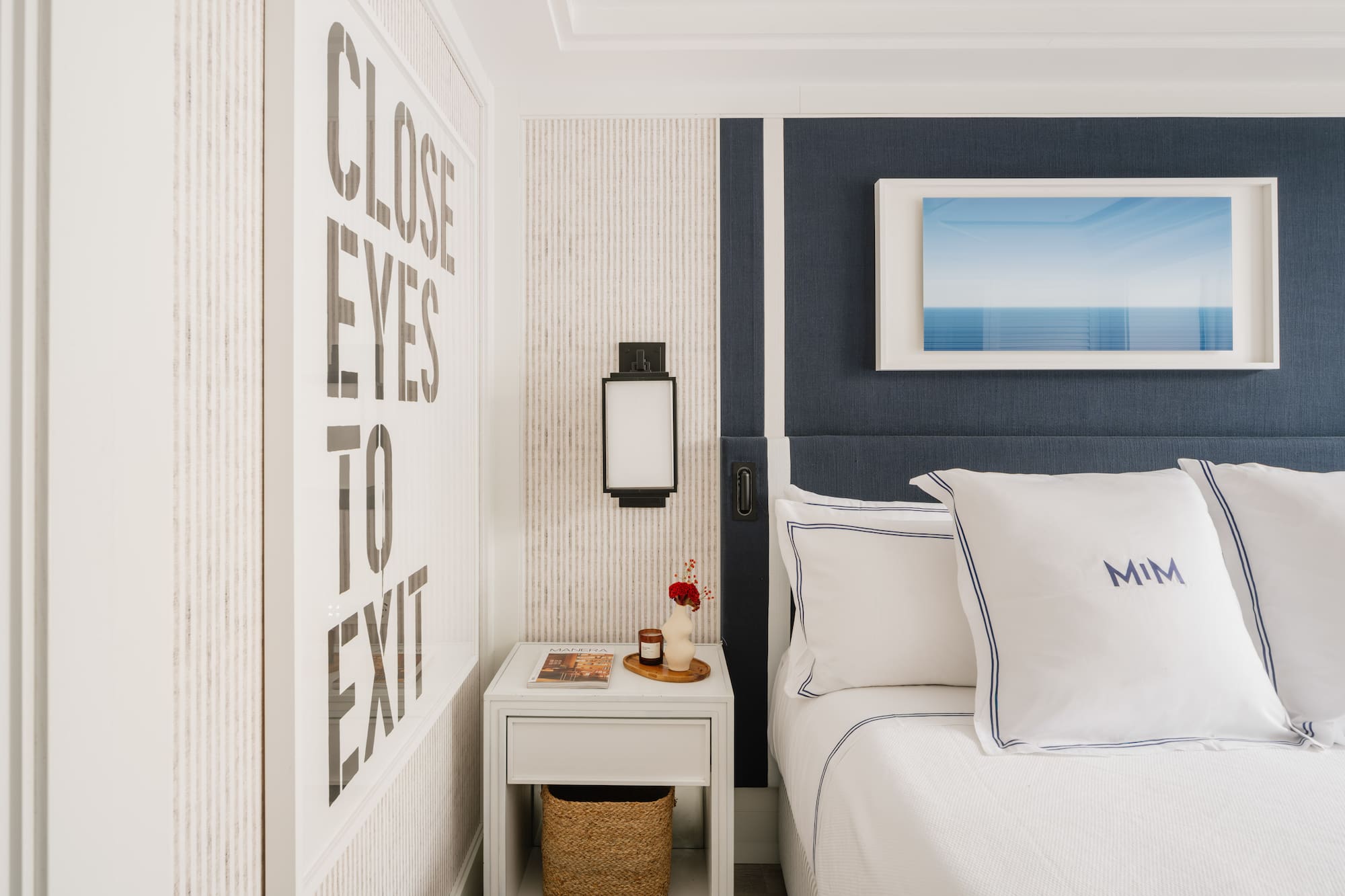 a bed with pillows and a basket on a nightstand