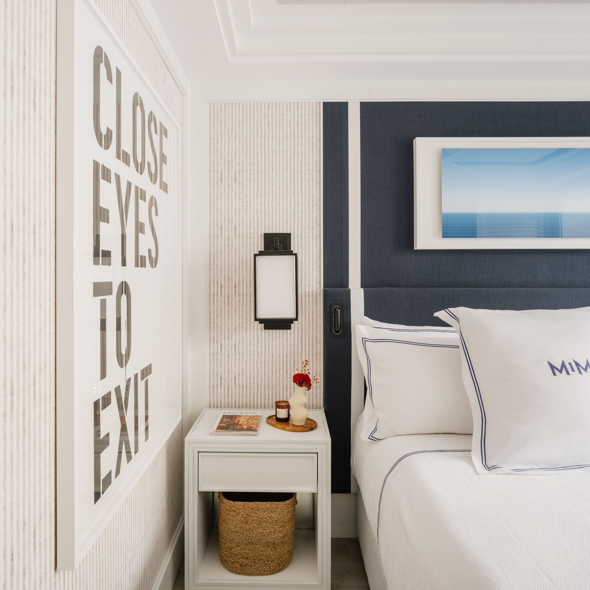 a bed with pillows and a basket on a nightstand