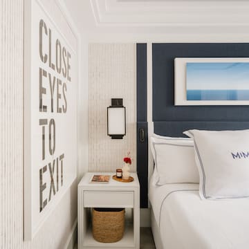 a bed with pillows and a basket on a nightstand