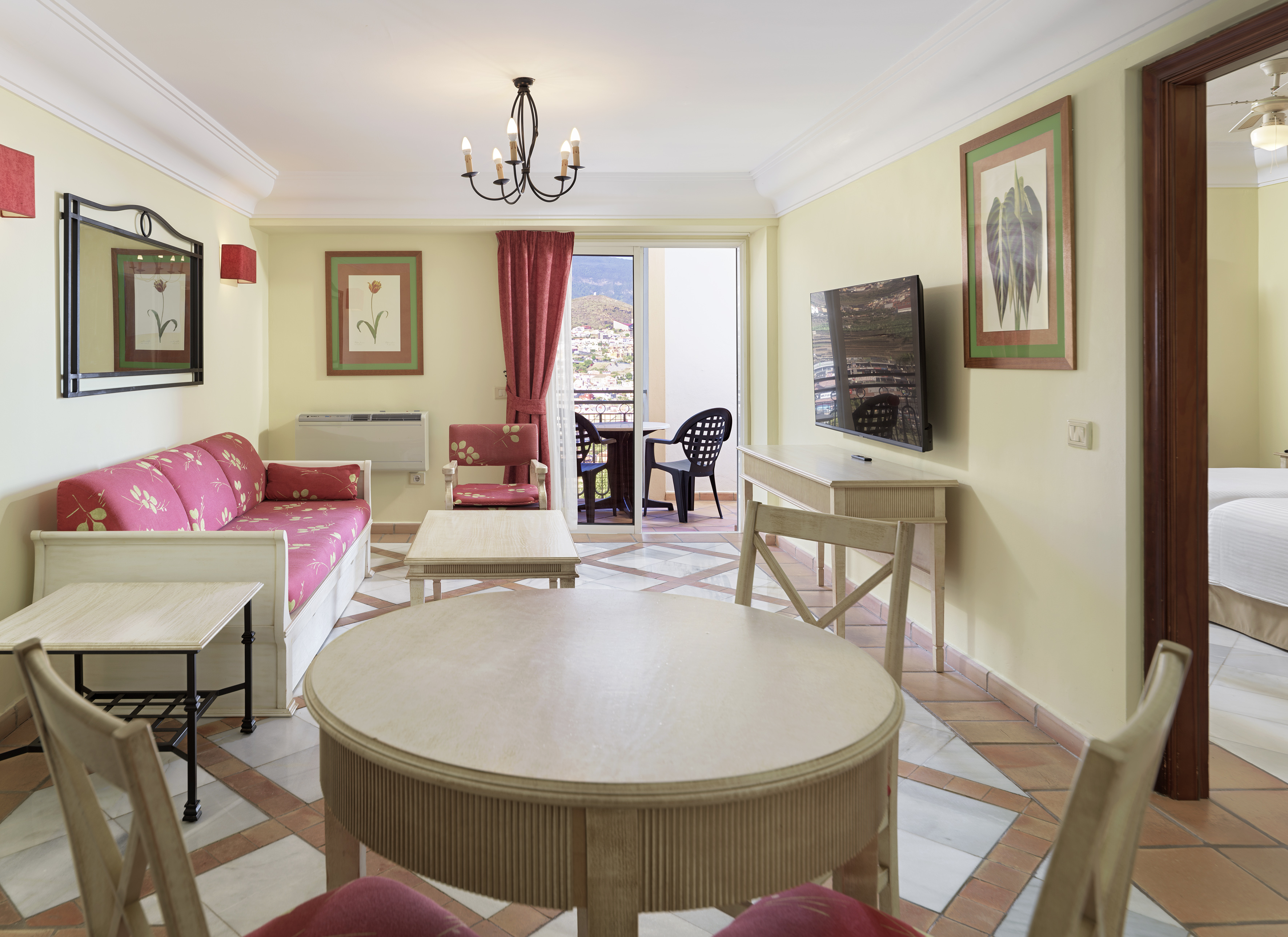 Apartment living room with sofa, dining table, TV, and balcony mountain view.