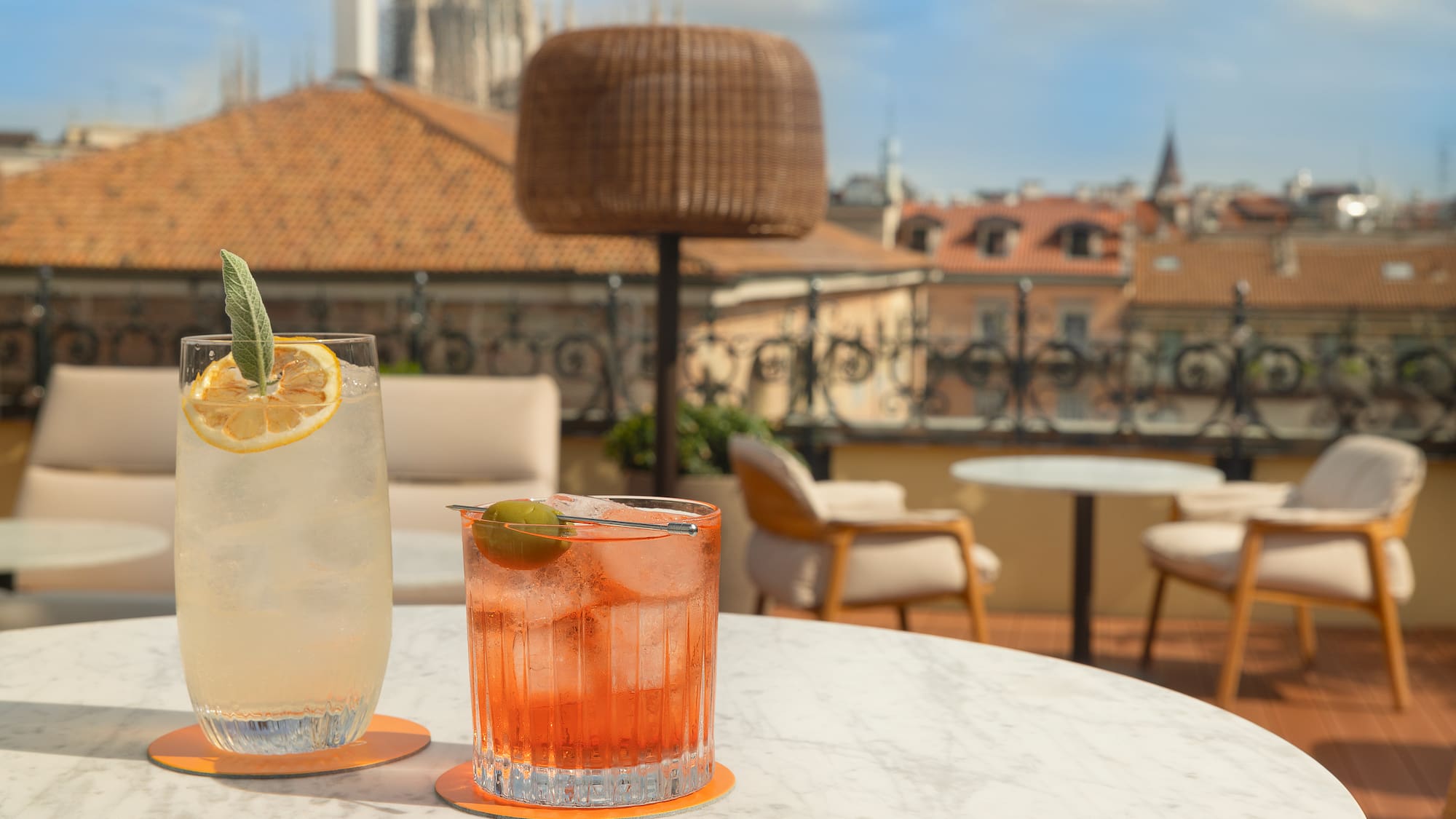 Refreshing cocktails on Milan rooftop terrace, Duomo cathedral cityscape.