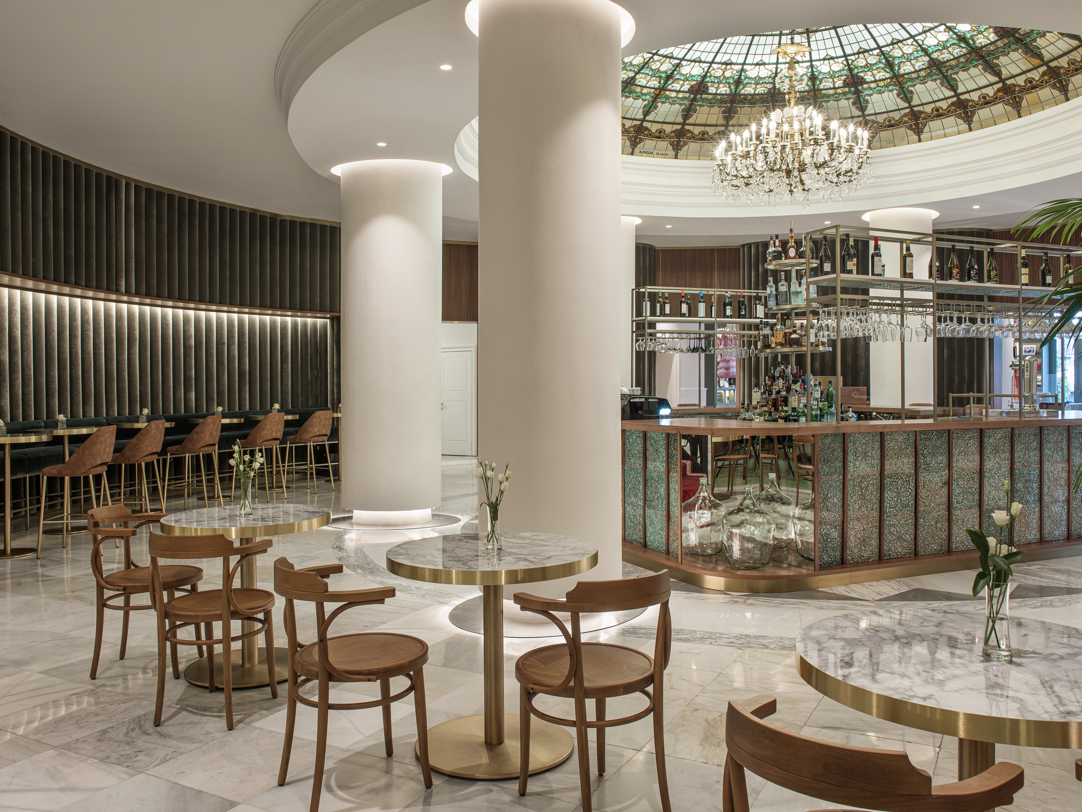 Luxury hotel bar with marble tables, modern decor, and stained glass dome.