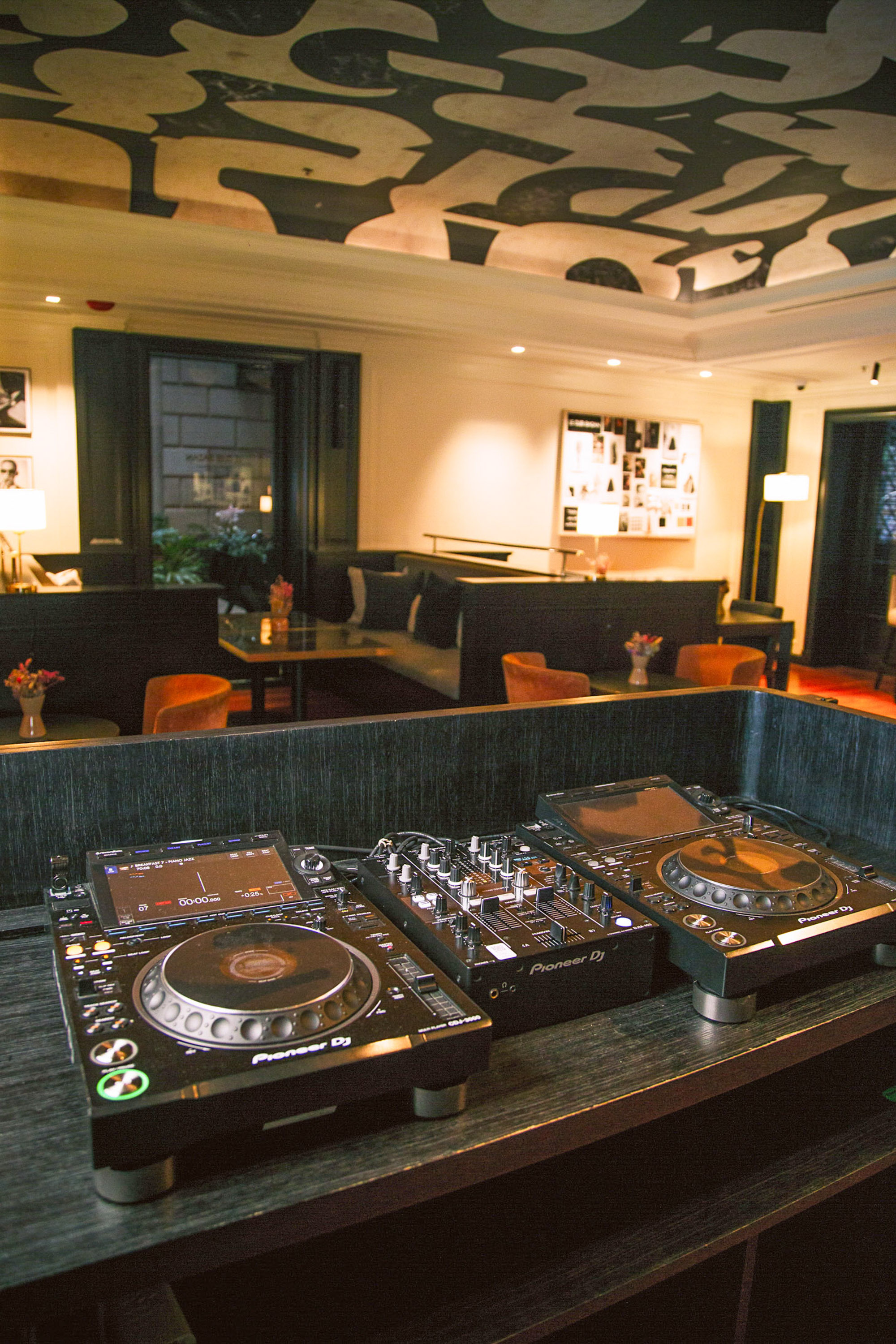 Consola DJ Pioneer en bar lounge de hotel moderno.