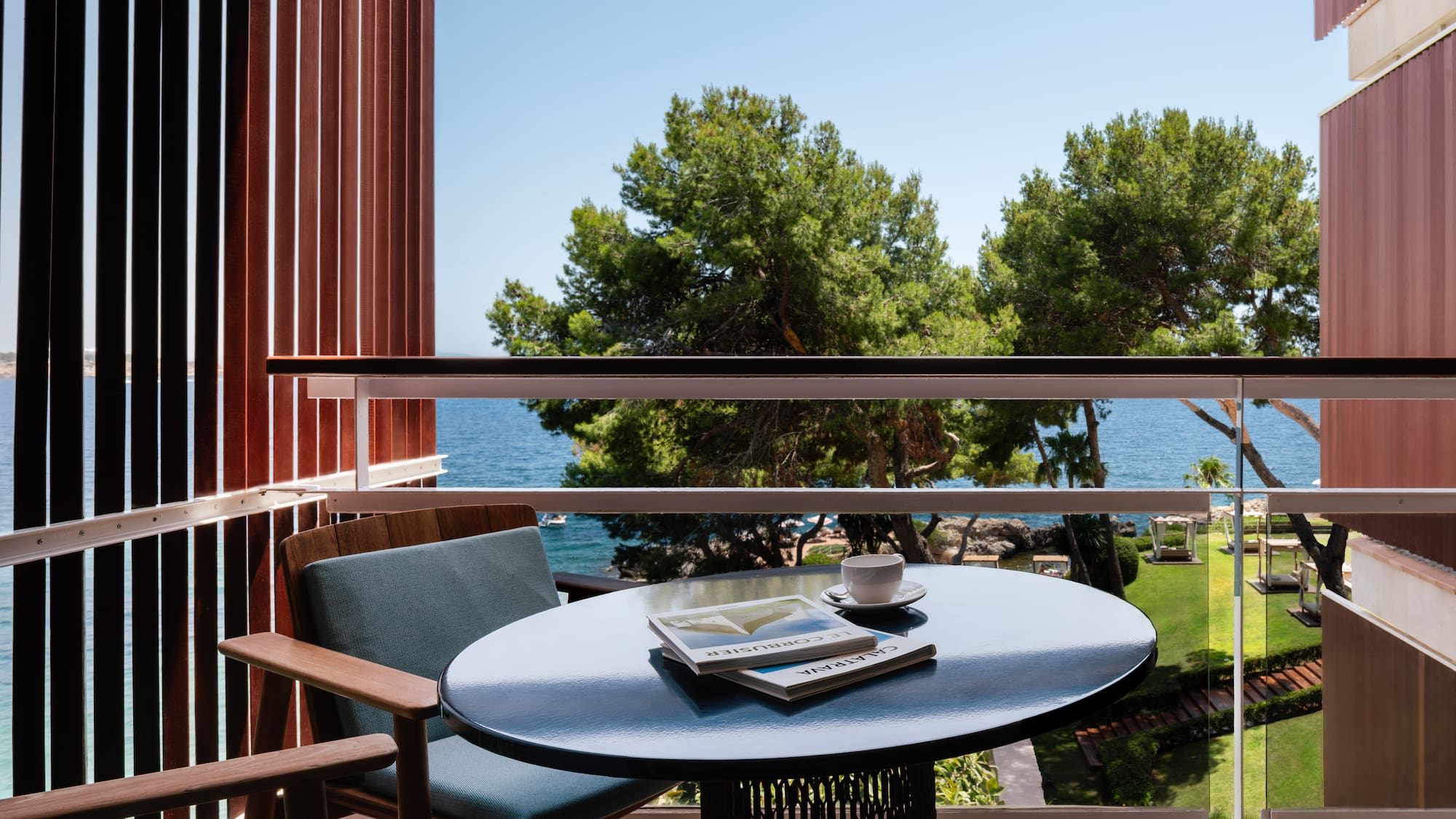 a table with a book and a cup on it outside of a balcony