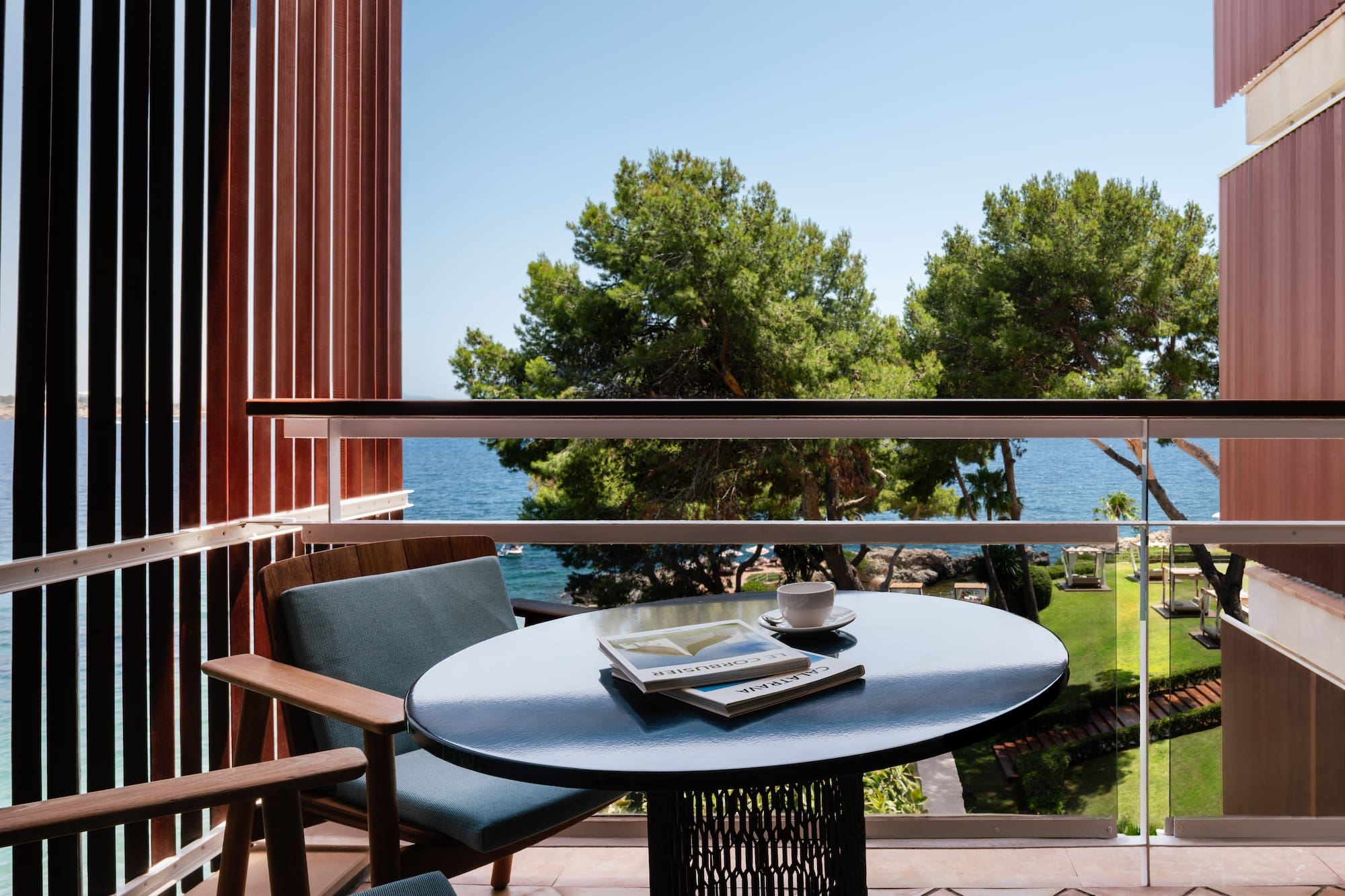 a table with a book and a cup on it outside of a balcony