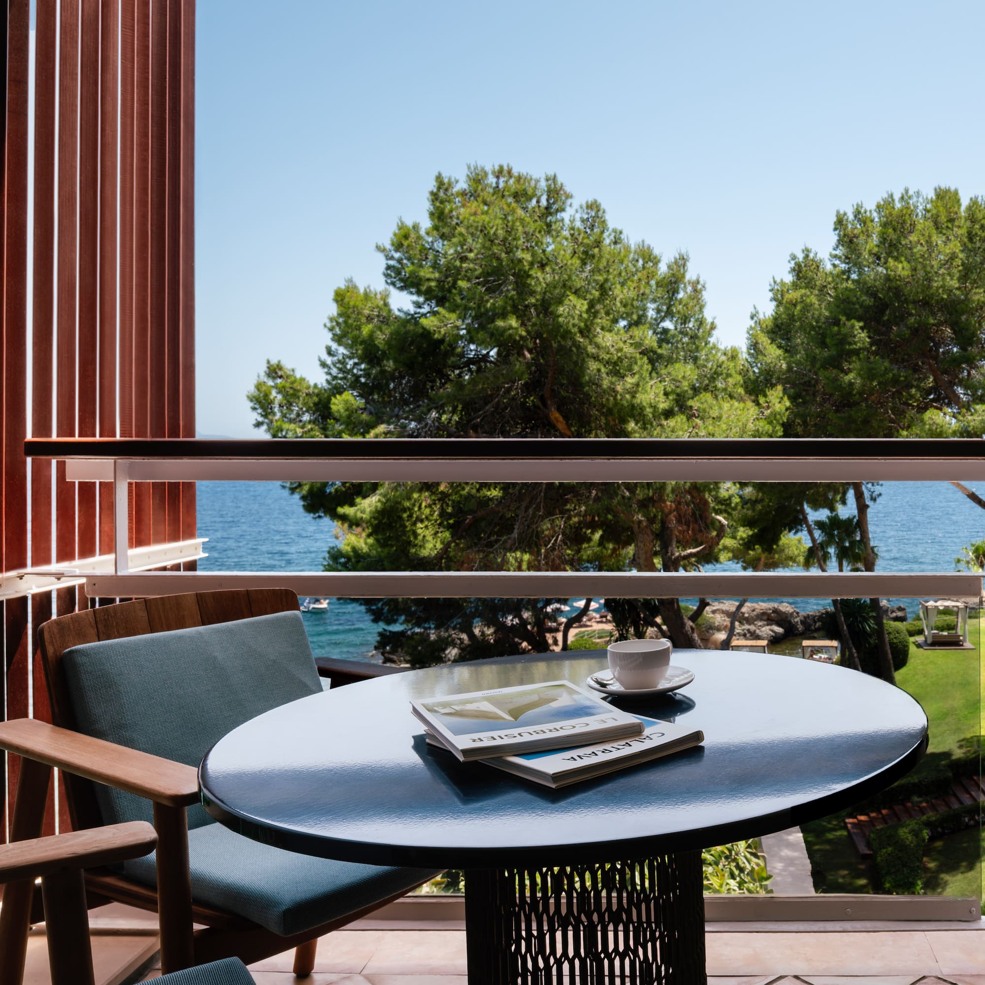 a table with a book and a cup on it outside of a balcony