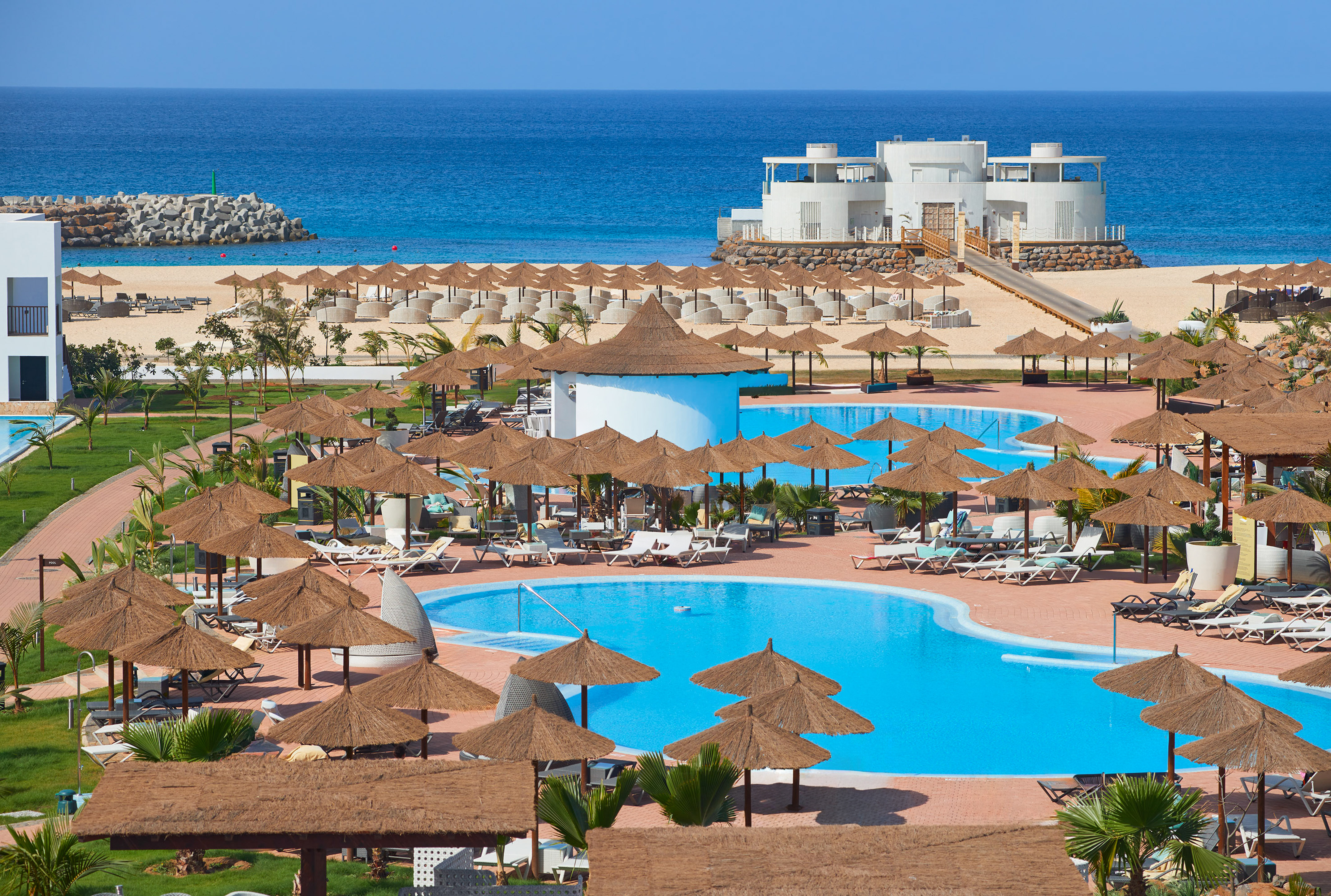 a pool with umbrellas and chairs on a beach
