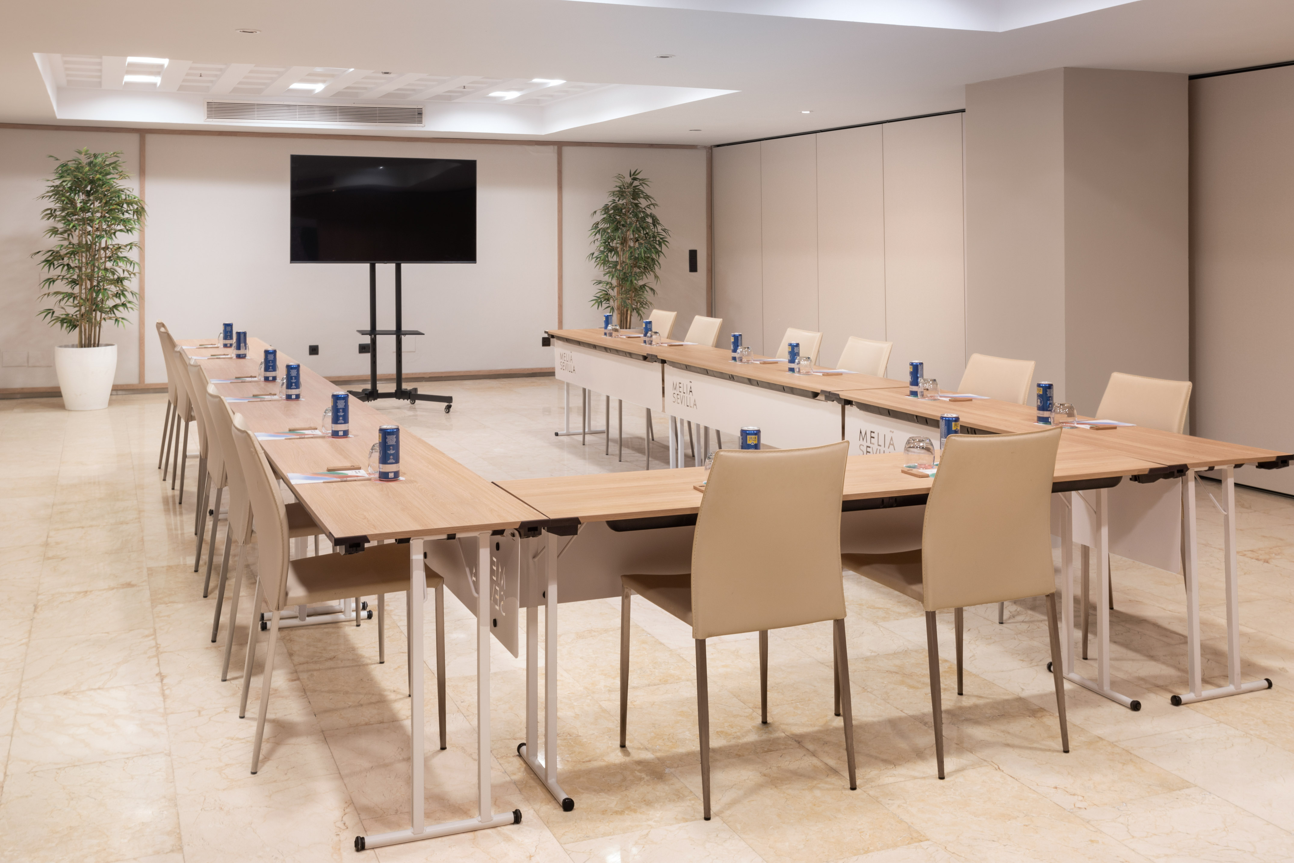 Meliá Sevilla U-shaped conference room with tables, chairs, and large TV.