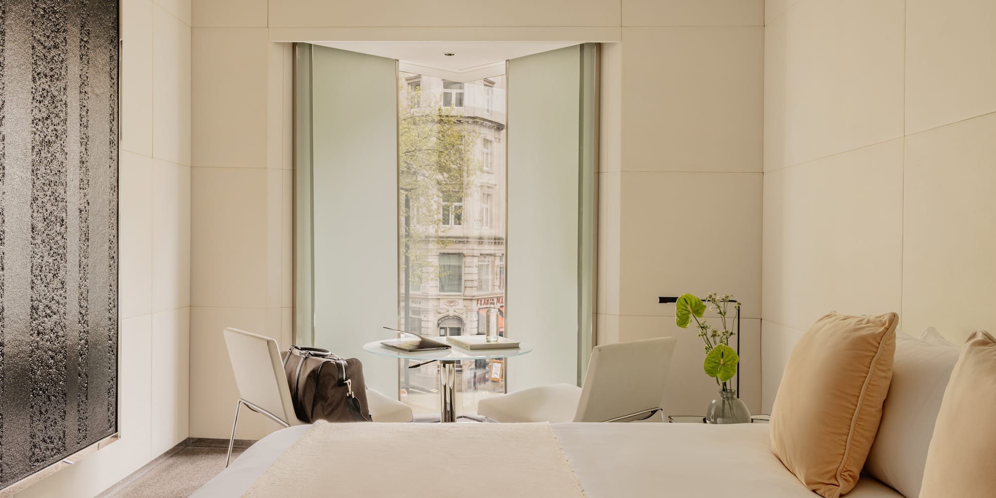 Deluxe King room at ME London Hotel with a comfortable bed, a chair with a table, and big window with city views.