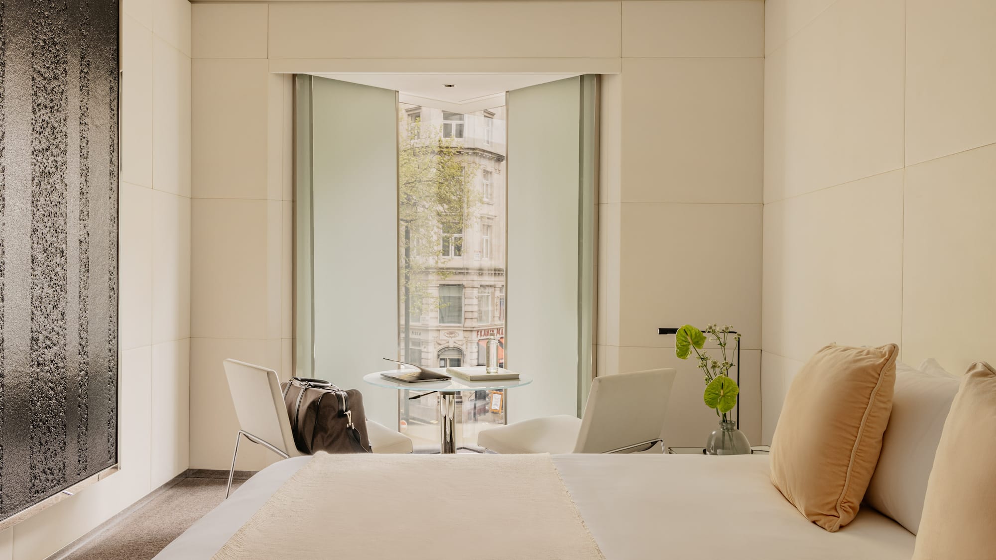 Deluxe King room at ME London Hotel with a comfortable bed, a chair with a table, and big window with city views.