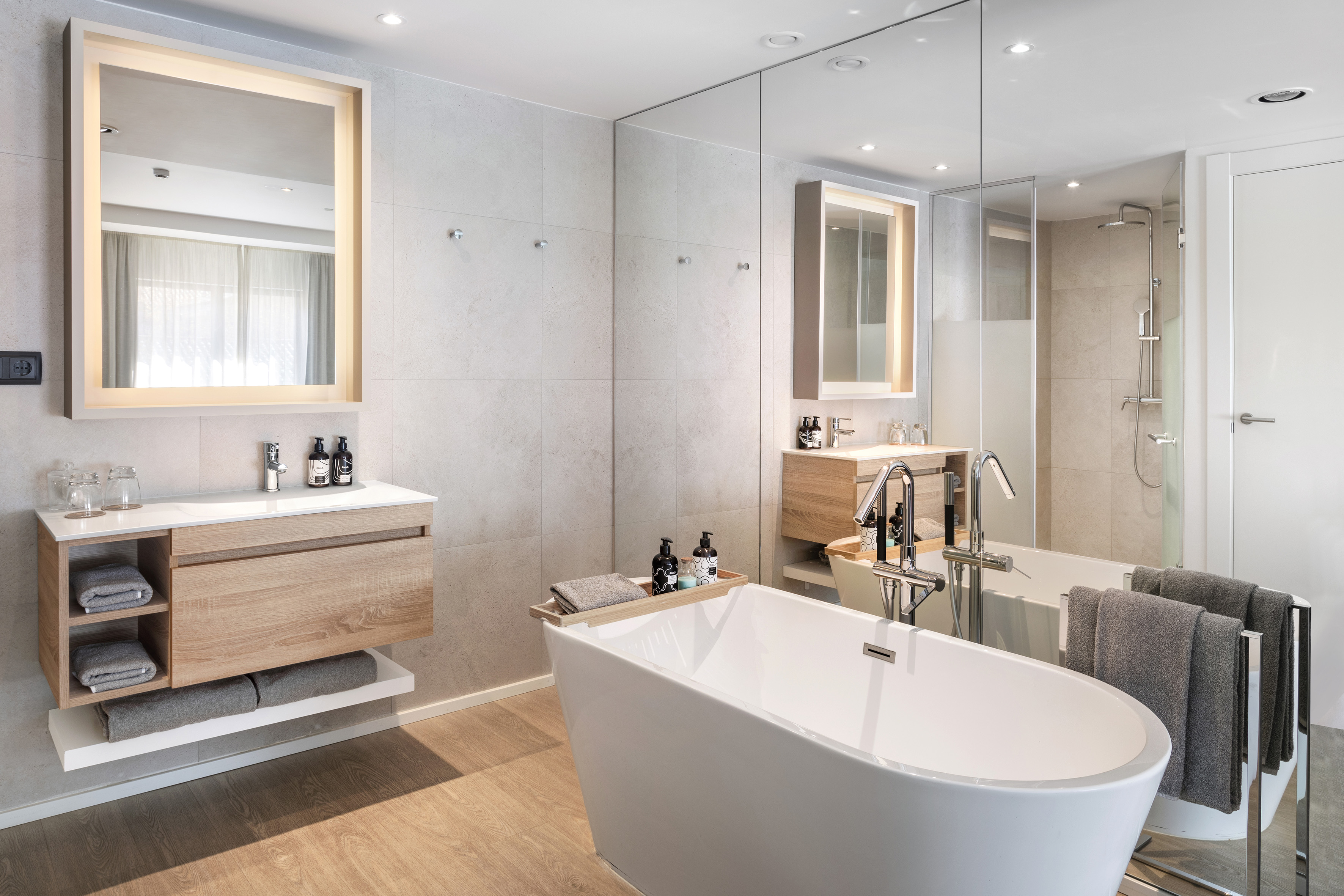 Bright modern bathroom with freestanding tub, wood vanity, and LED mirror.