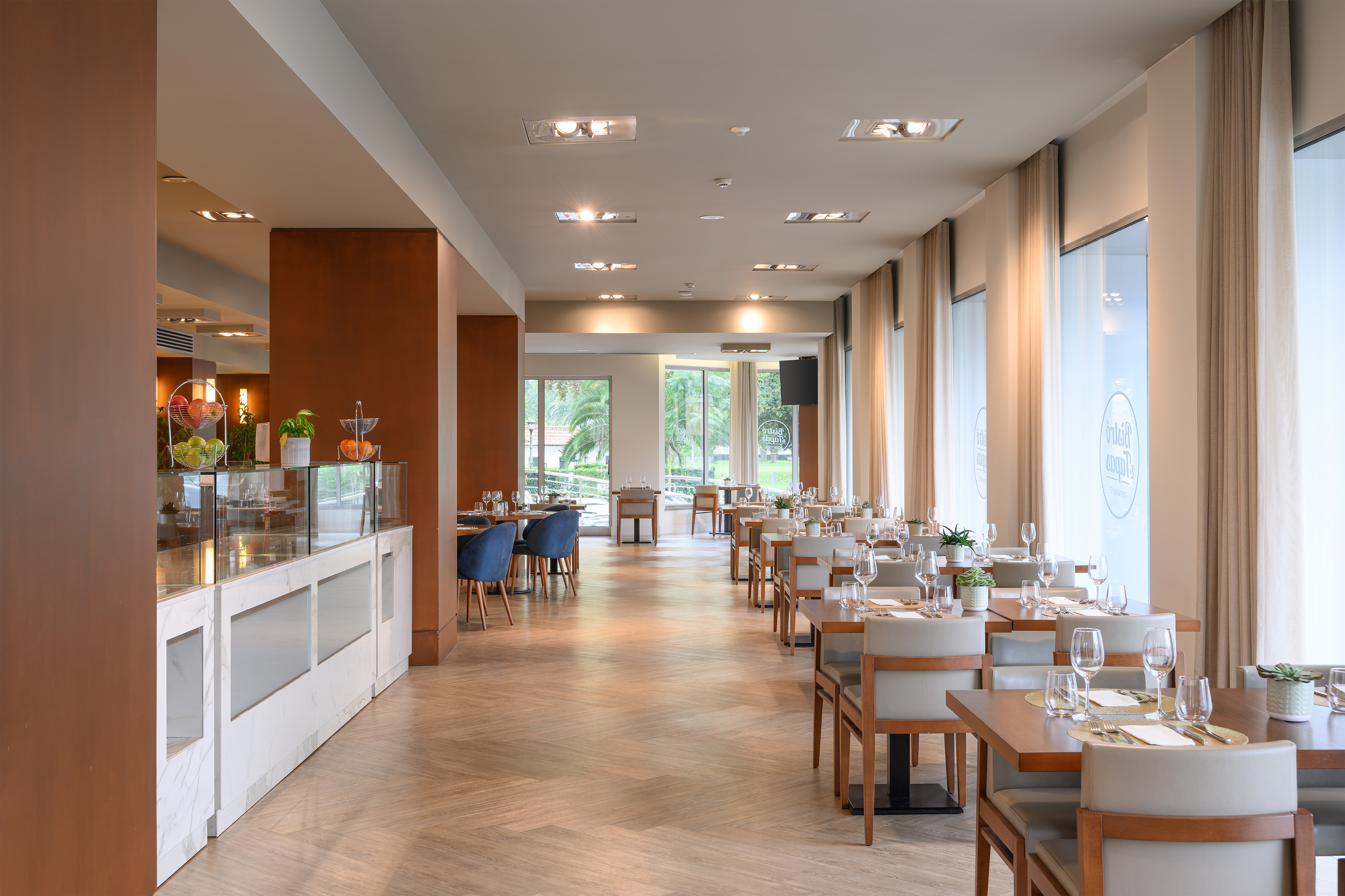 Spacious modern hotel dining room with set tables and buffet.