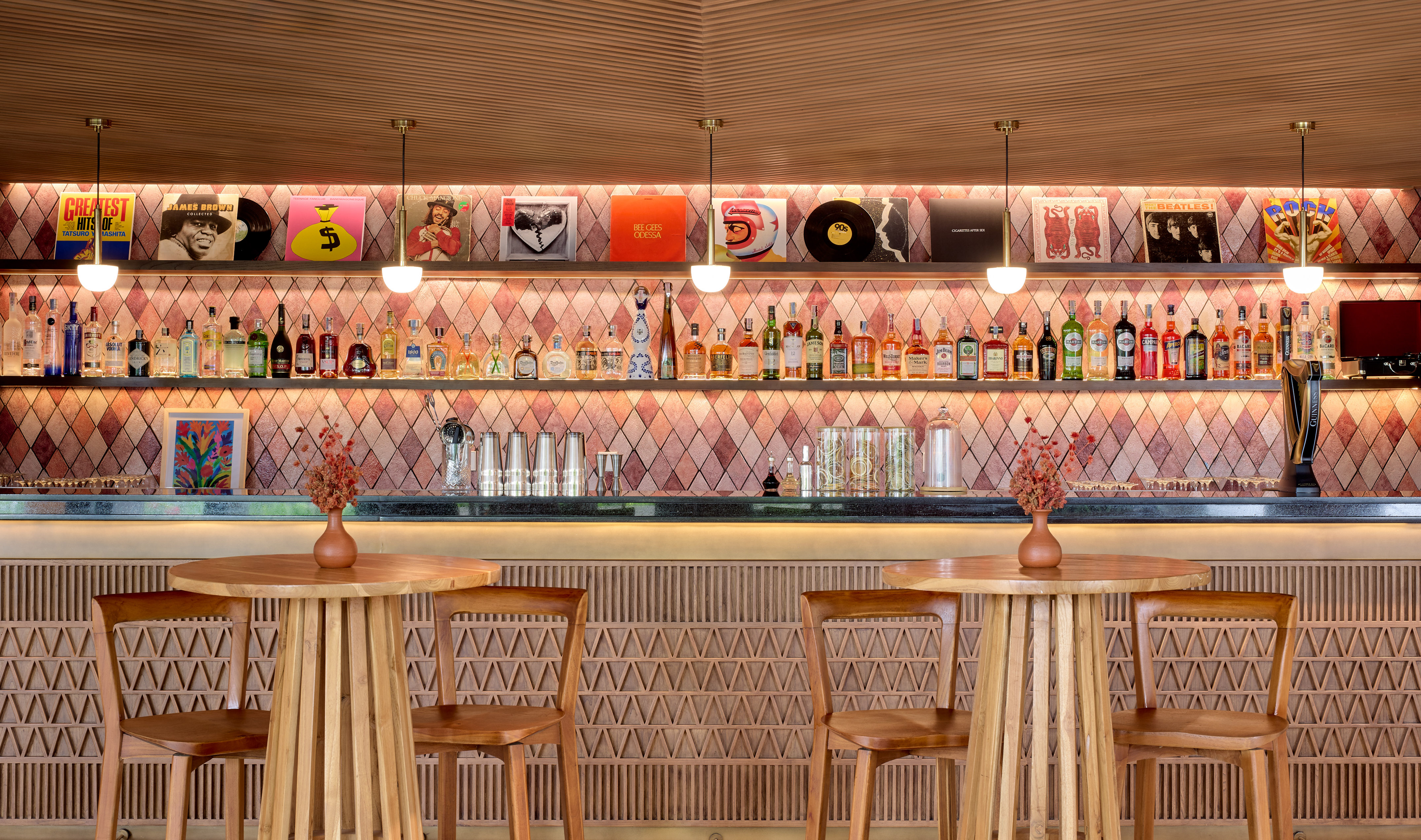 Modern bar with liquor display, vintage vinyl records, and wooden tables.