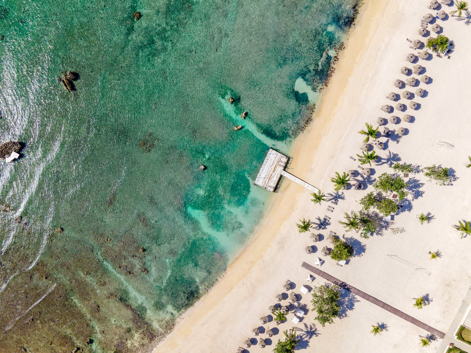 a beach with a dock and umbrellas