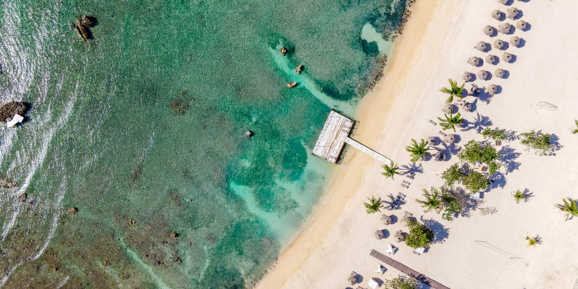 a beach with a dock and umbrellas