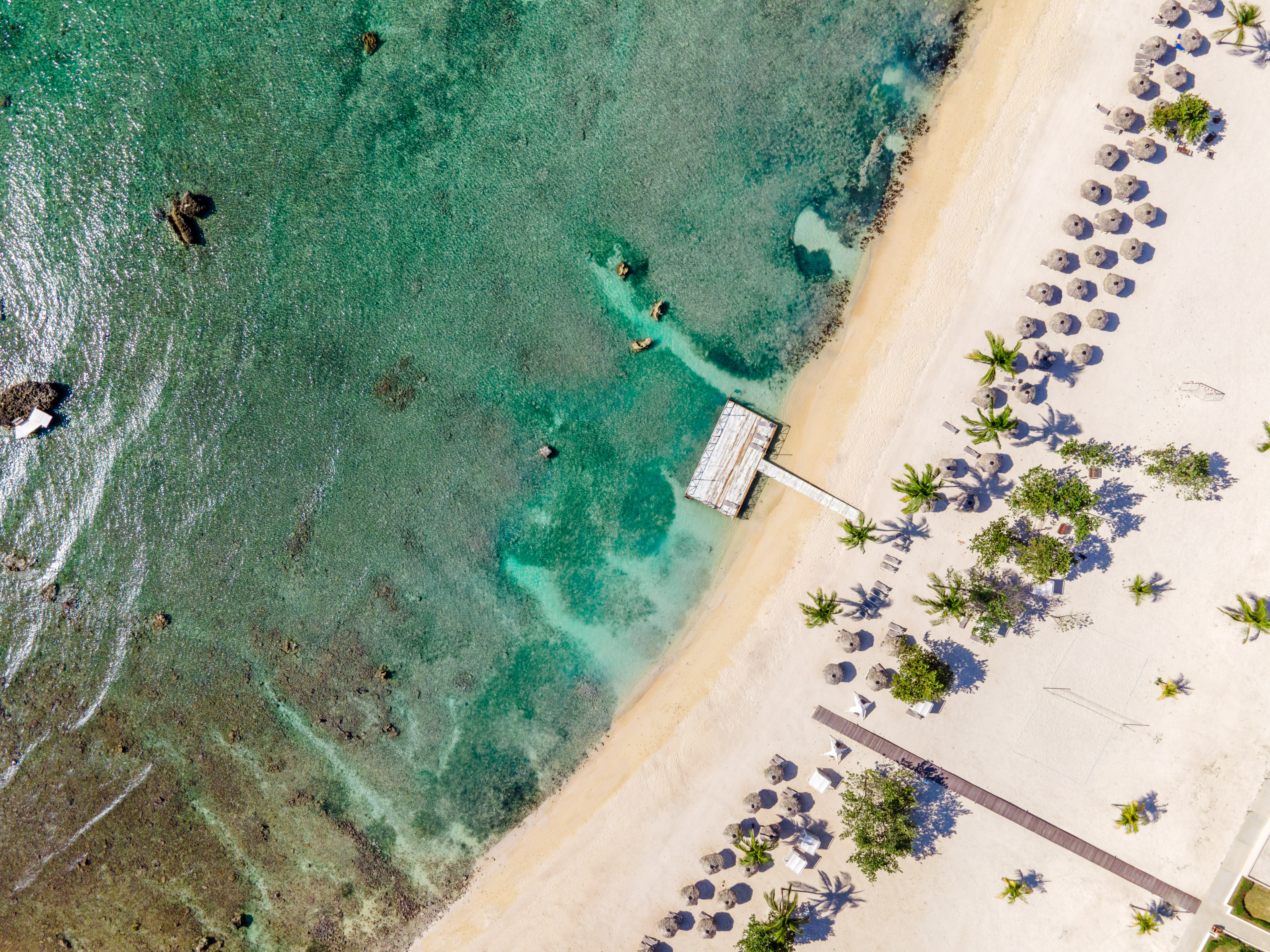 a beach with a dock and umbrellas