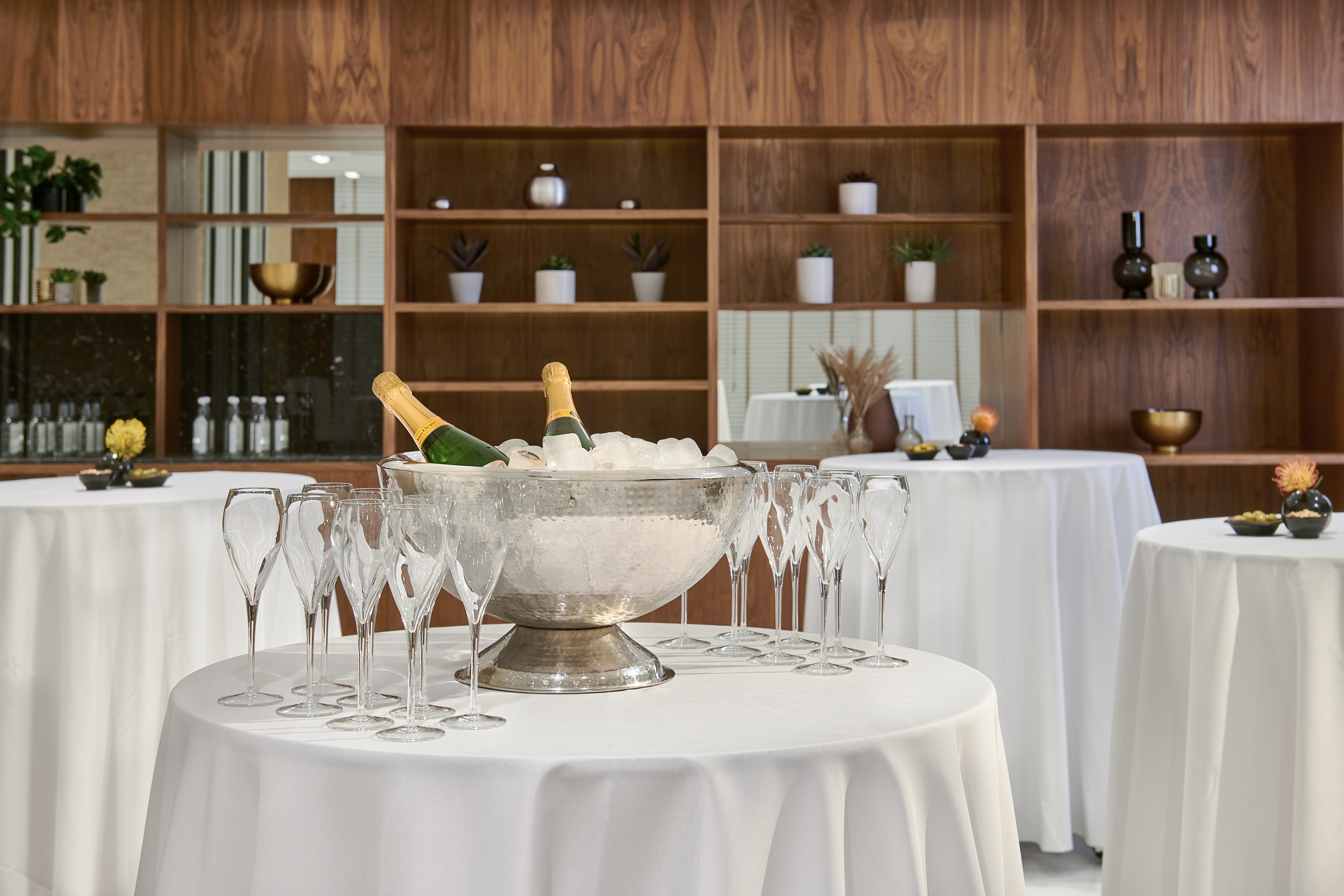 Champagne bottles and flutes on white tables for a reception event.