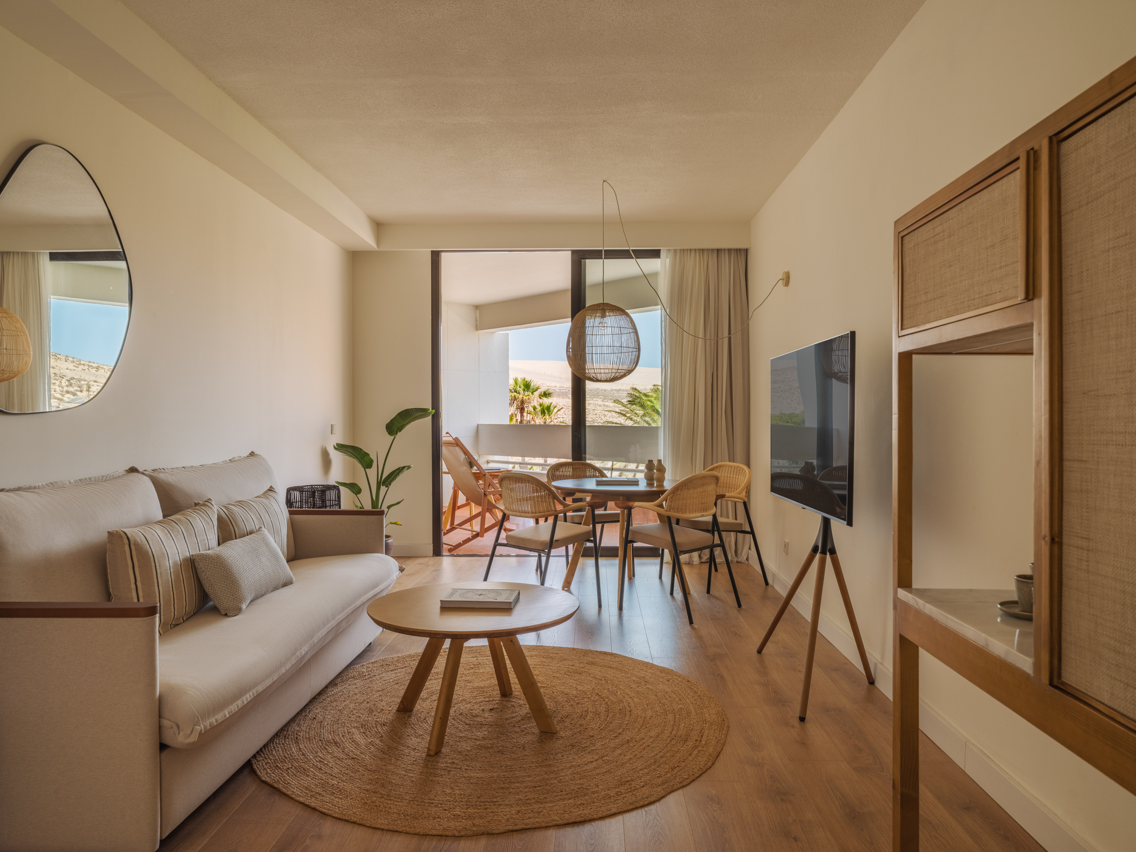 Modern neutral living room, desert balcony view, beige sofa, rattan decor.
