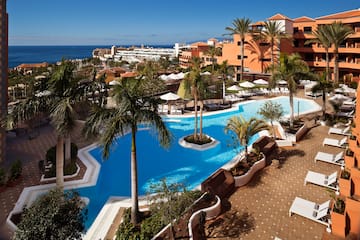a pool with palm trees and a beach in the background
