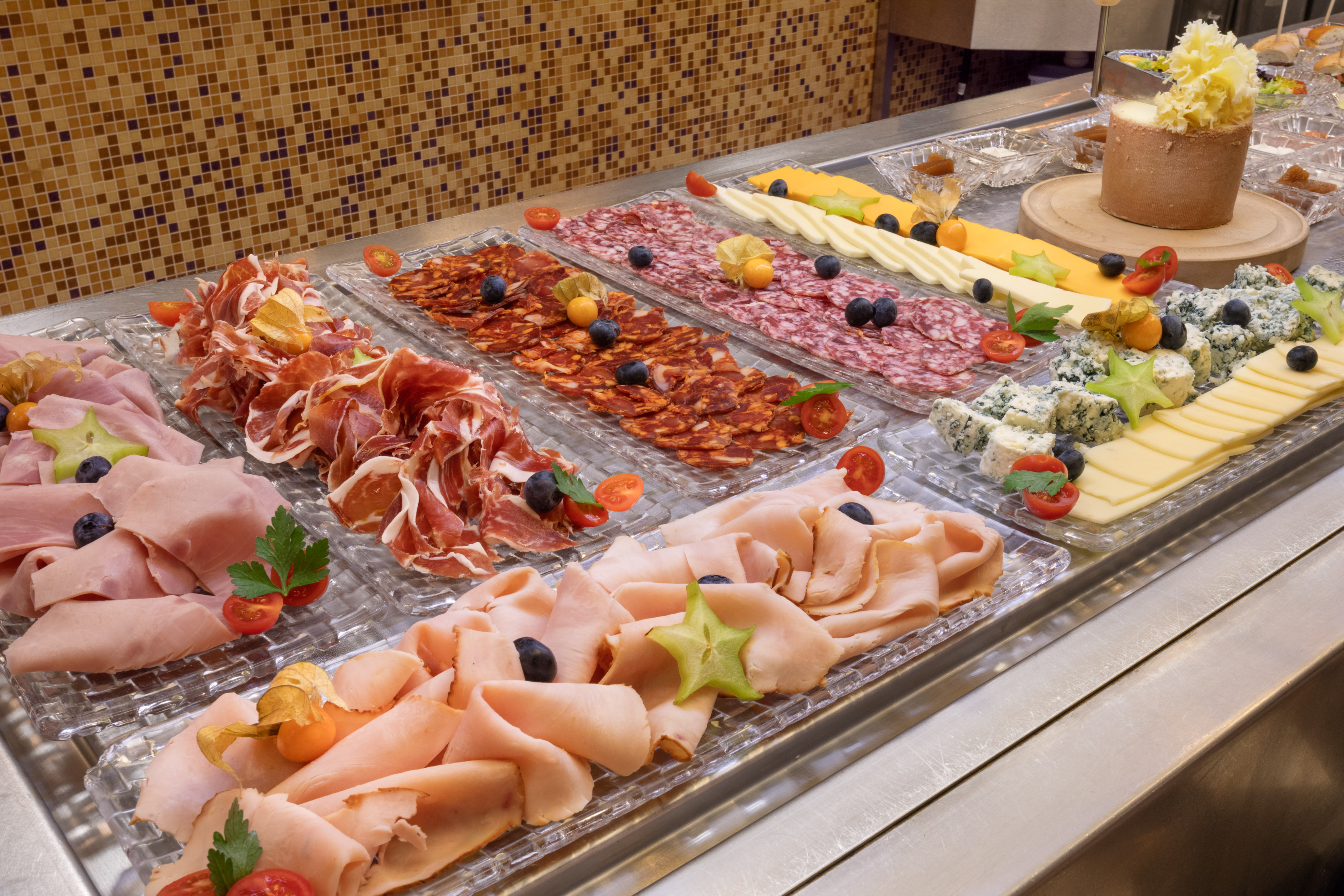 Charcuterie and cheese buffet with sliced meats, cheeses, and fruit.