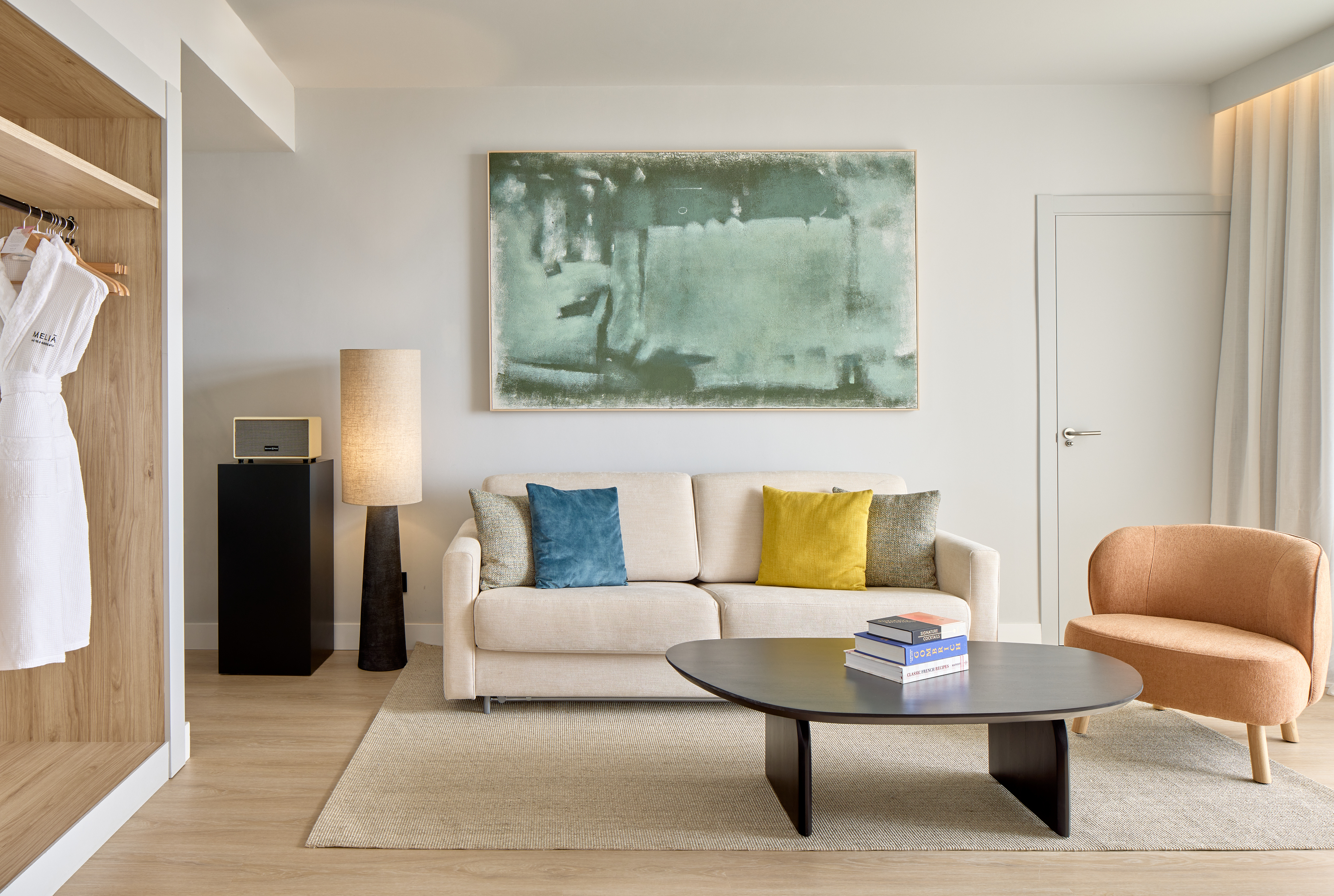Salón moderno suite Meliá con sofá, sillón, mesa de centro y arte abstracto.