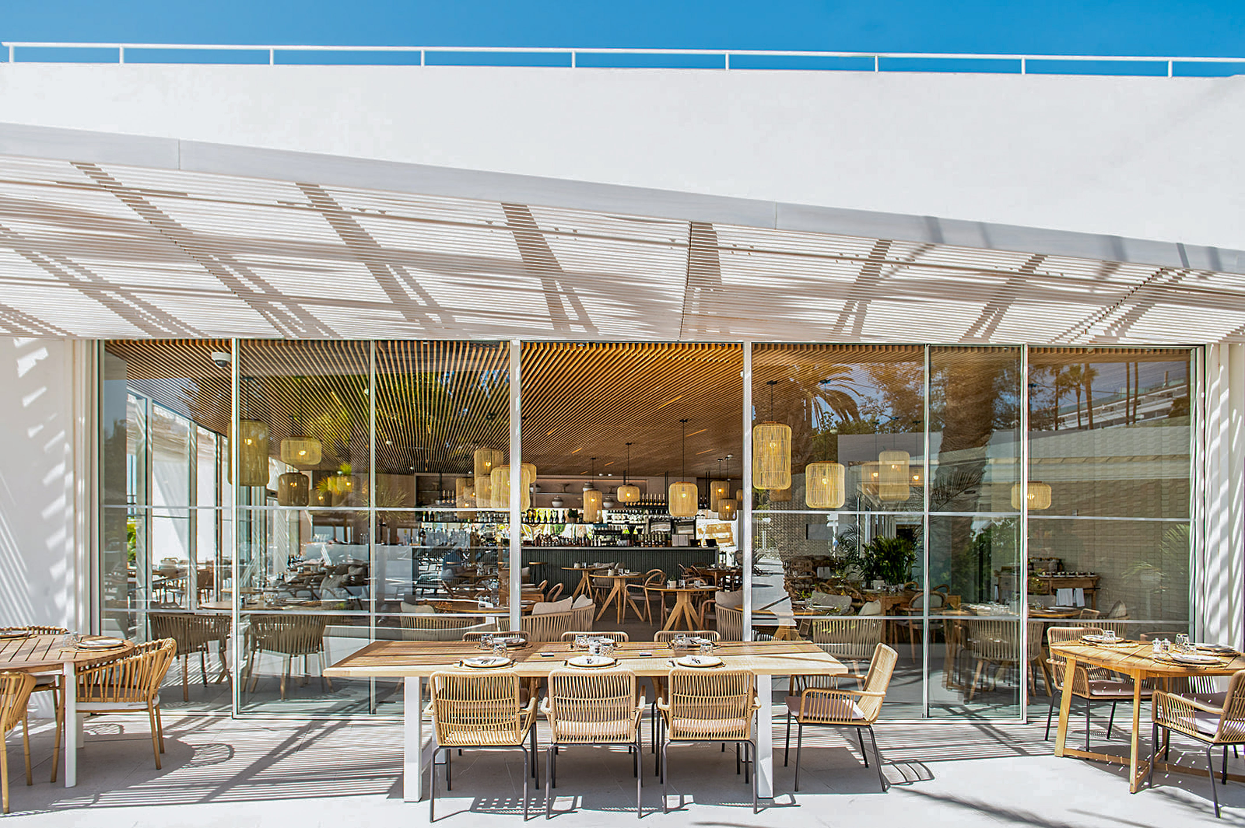 Modern restaurant terrace with outdoor dining and visible bar interior.