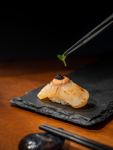 a pair of chopsticks holding a piece of sushi