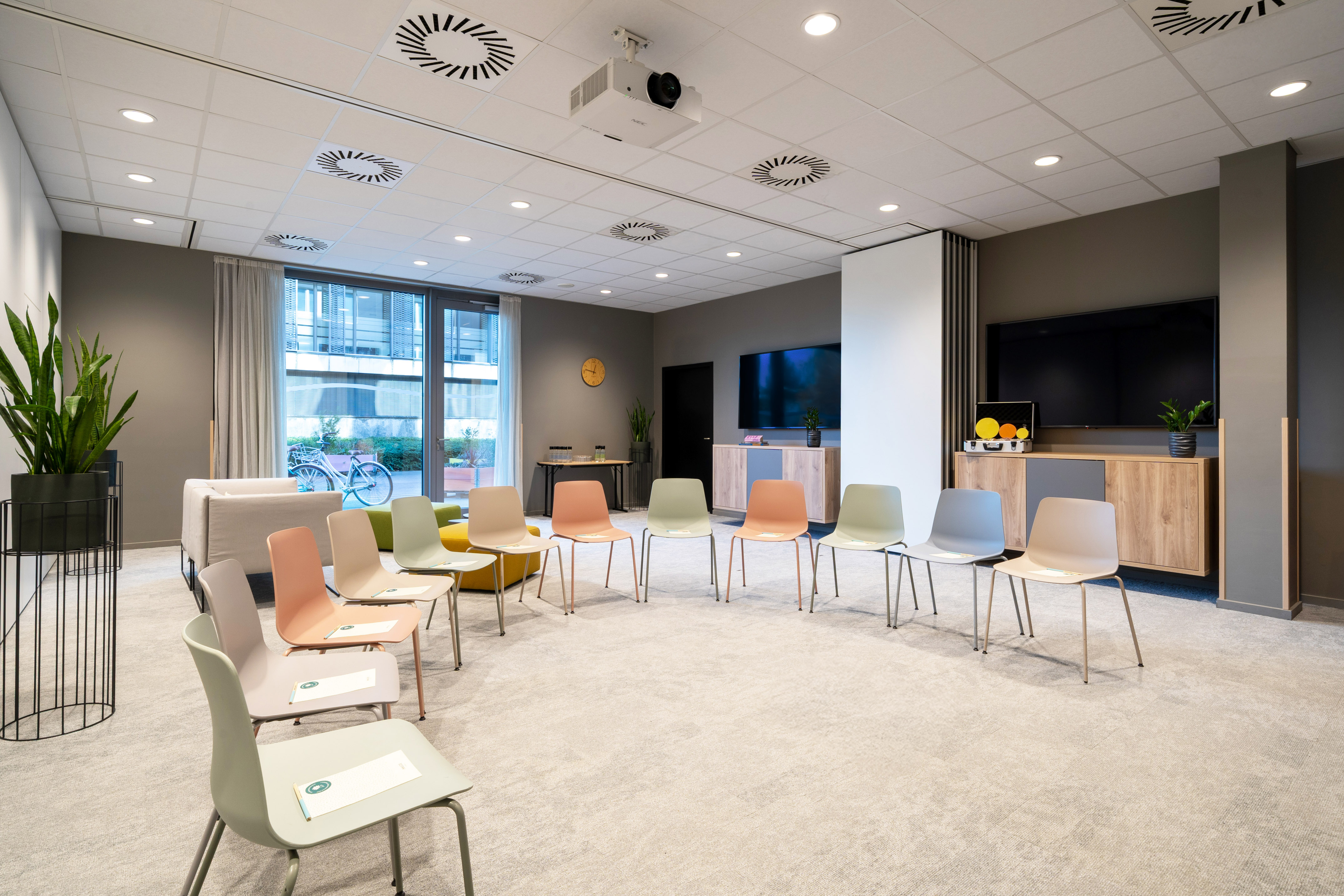 Modern meeting room with colorful chairs, projector, and presentation screen.