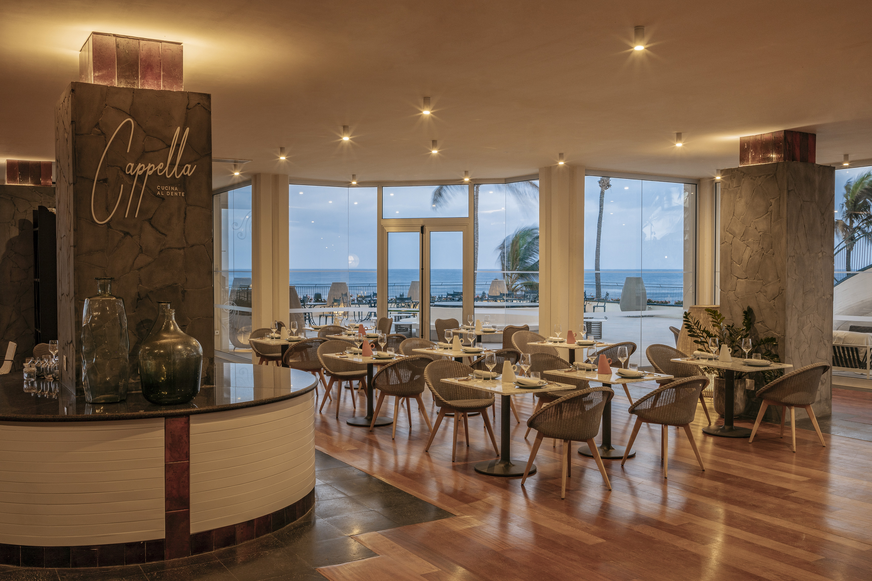 Elegant Cappella restaurant interior with ocean view, set tables, and modern decor.