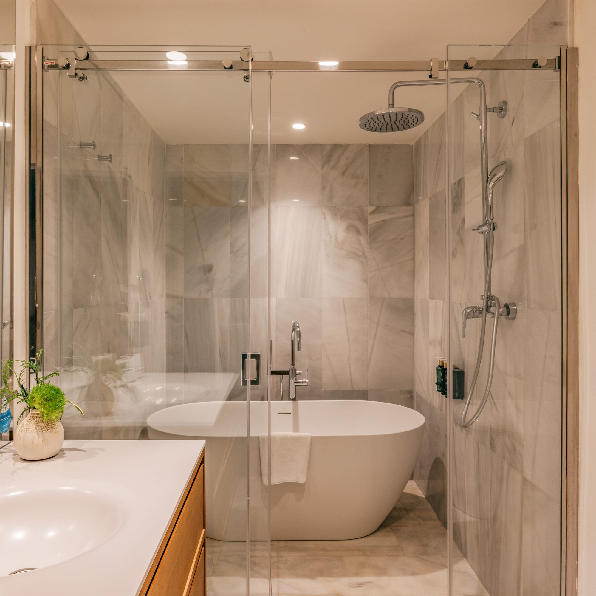 Modern bathroom with marble shower, freestanding tub, glass enclosure, and vanity.