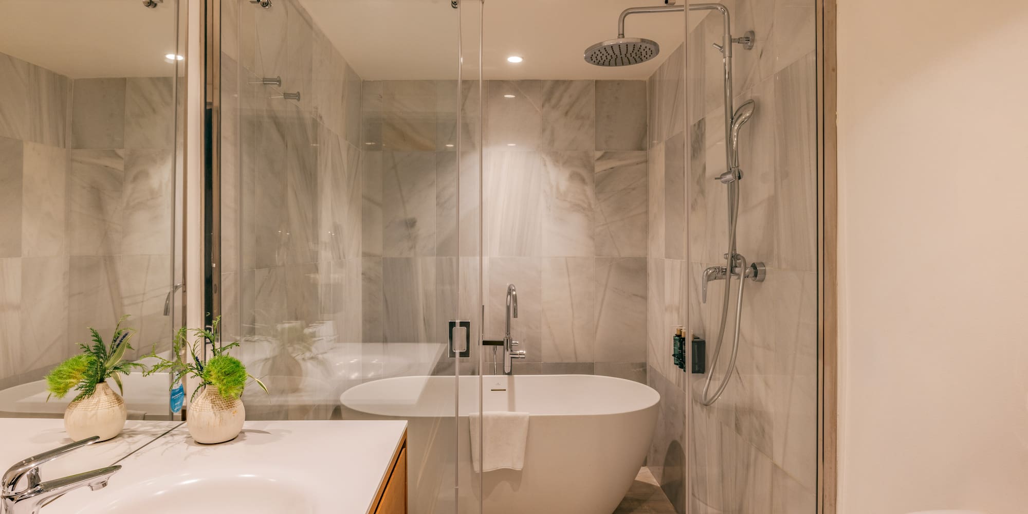 Modern bathroom with marble shower, freestanding tub, glass enclosure, and vanity.