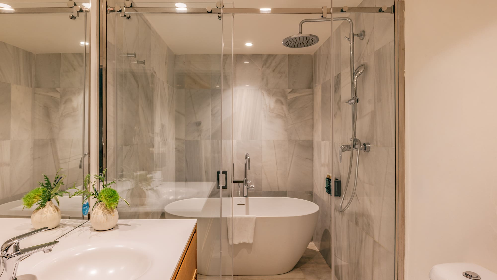 Modern bathroom with marble shower, freestanding tub, glass enclosure, and vanity.